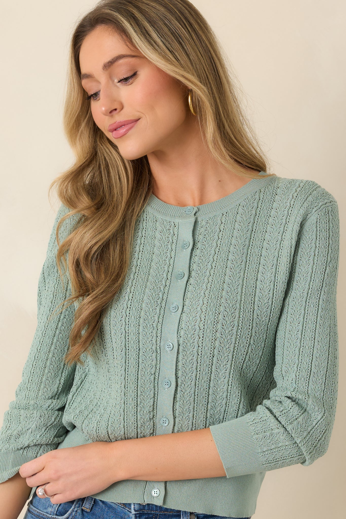 Close view of the eyelet knit texture and crew neckline, highlighting the lightweight openwork detailing throughout the cardigan.