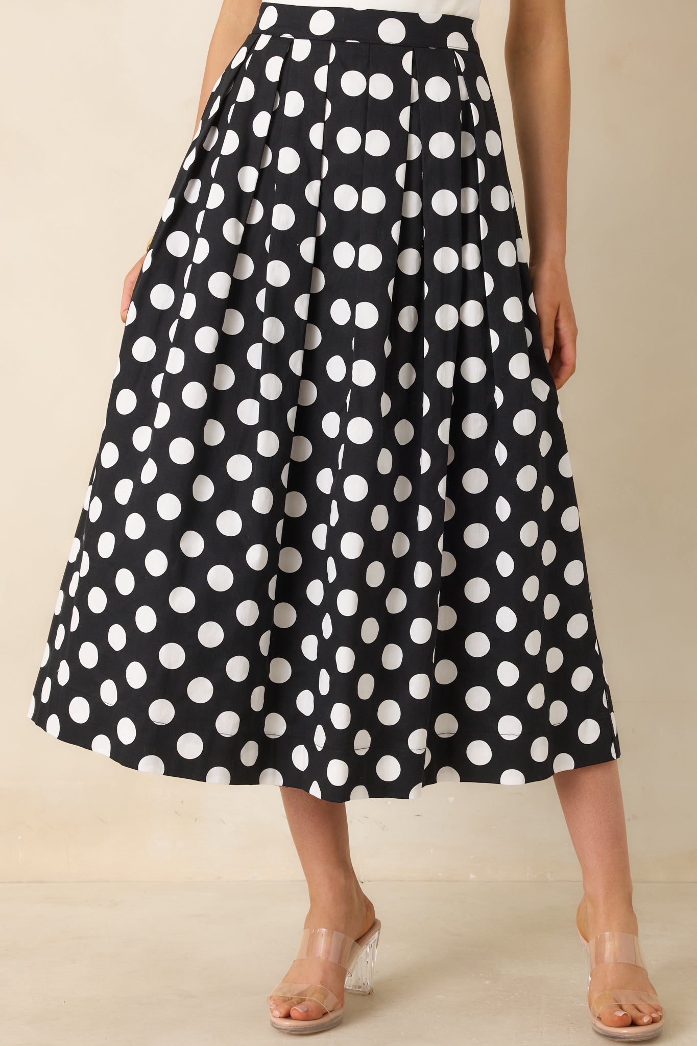 Detailed close-up of skirt highlighting polka dot pattern, pleated texture, and hidden zipper construction.