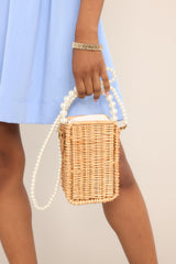 This bamboo bag features a faux pearl top handle, a removable faux pearl strap, and a cloth drawstring closure.