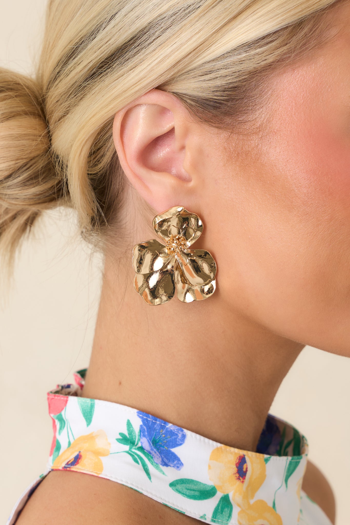 Cropped front view of gold floral statement earrings with hammered petals and an oversized bloom design.