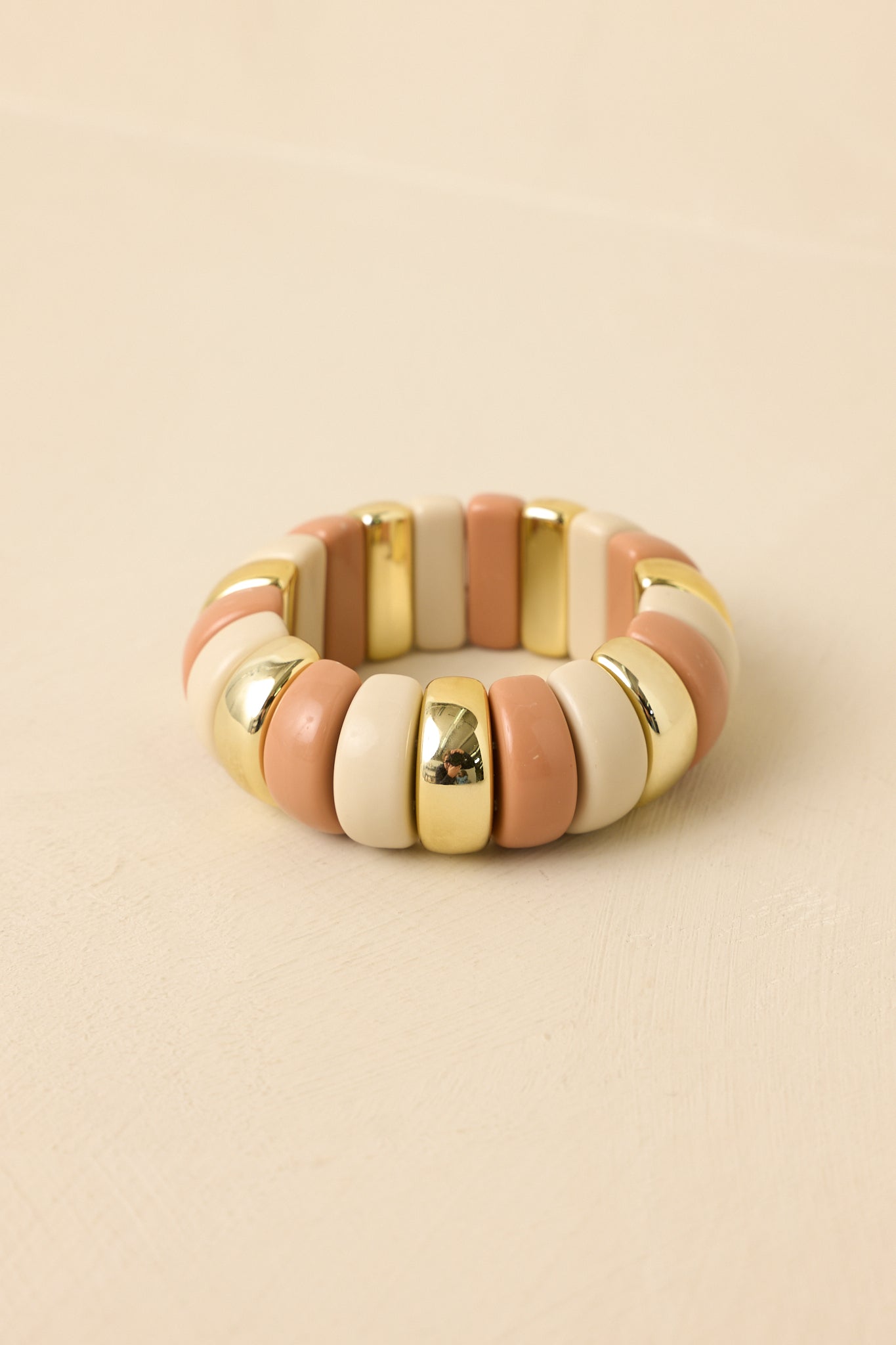 Detailed close-up of multi-beaded bracelet highlighting blush pink and ivory sculptural beads with polished gold accents on a stretch band.