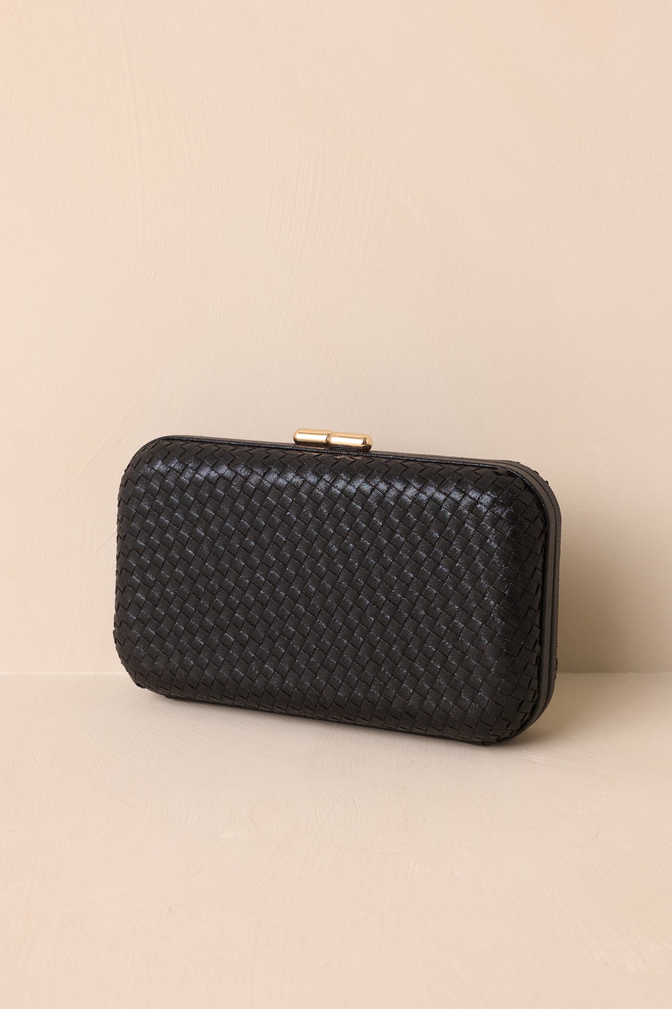 A full view of the black clutch with a rectangular structured shape, woven design, and rounded edges.