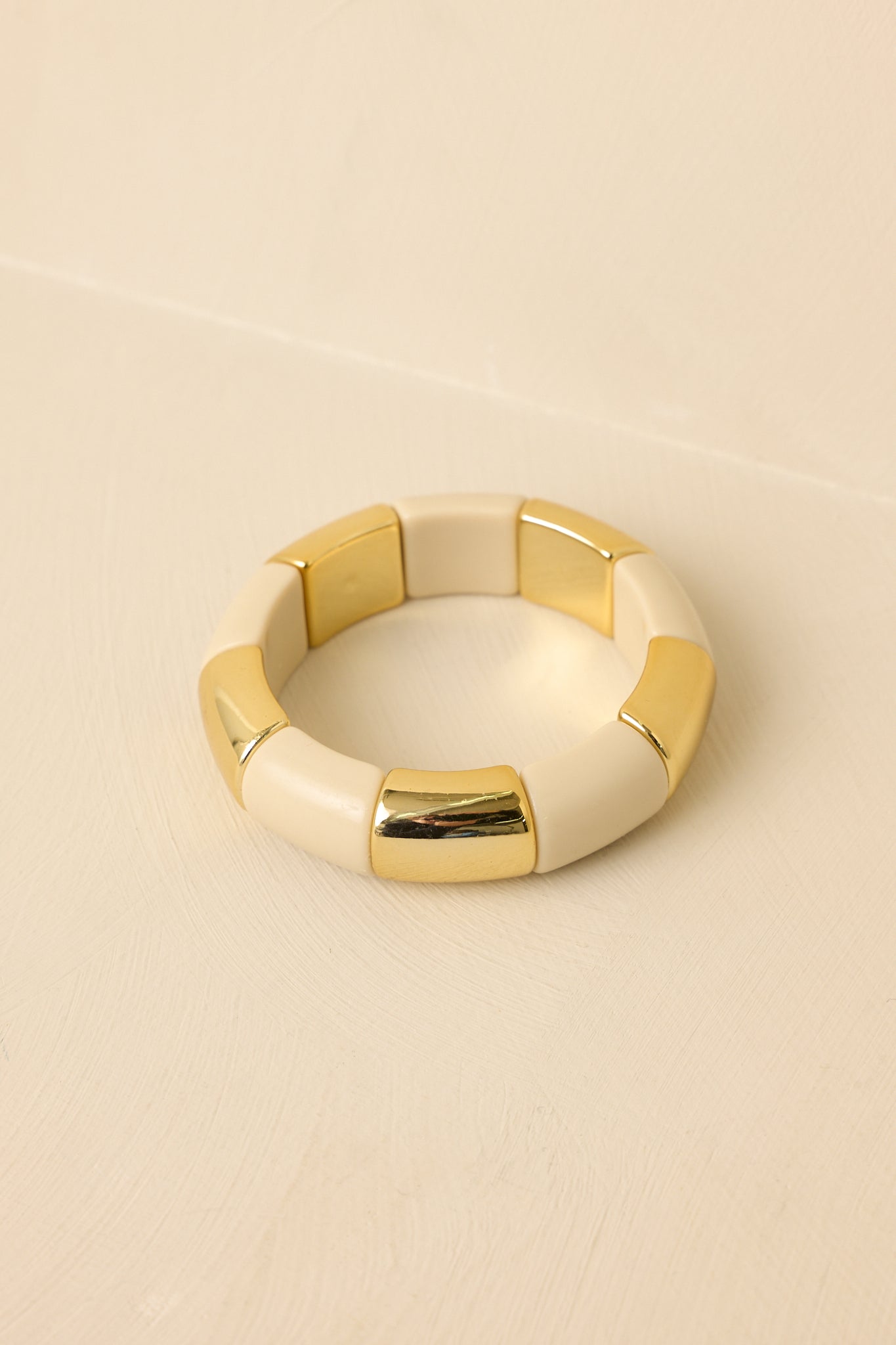 Close-up of ivory and gold bracelet showing bead texture, smooth finish, and slip-on construction.