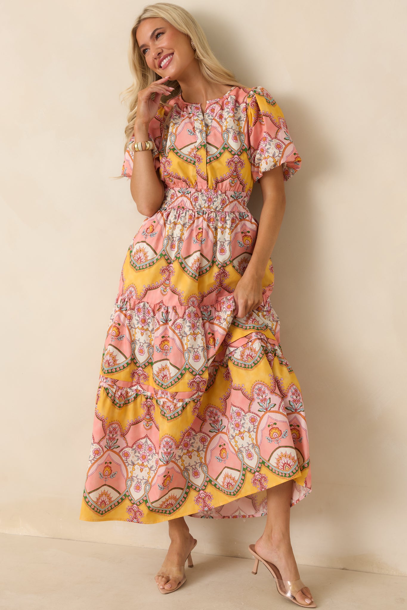 Pink and marigold midi dress in 100% cotton featuring a colorful vintage-inspired ornamental scarf print, short bubble sleeves, and a flowing tiered skirt.