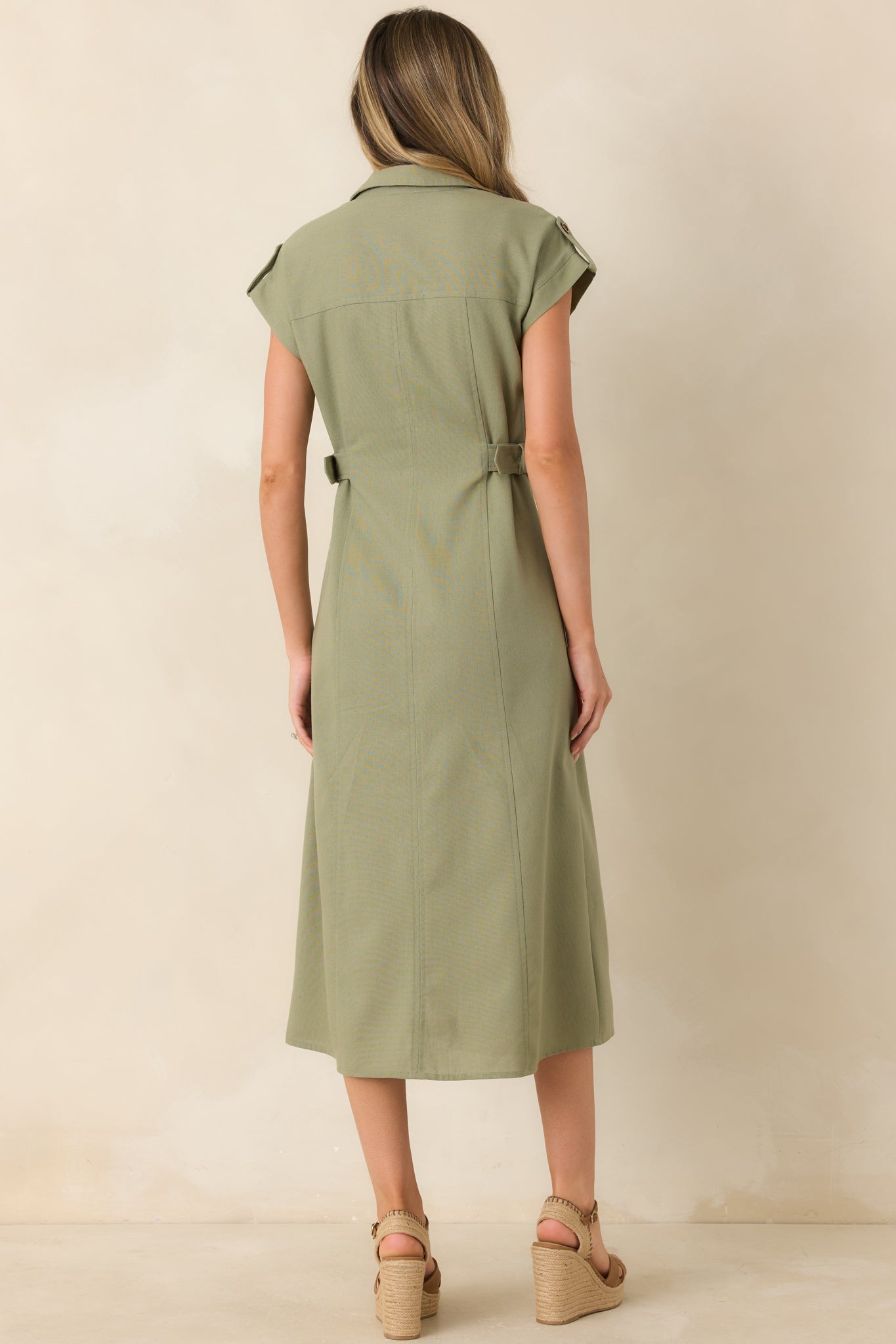 Rear view of sage green utility midi dress with structured silhouette and short sleeve tab details.