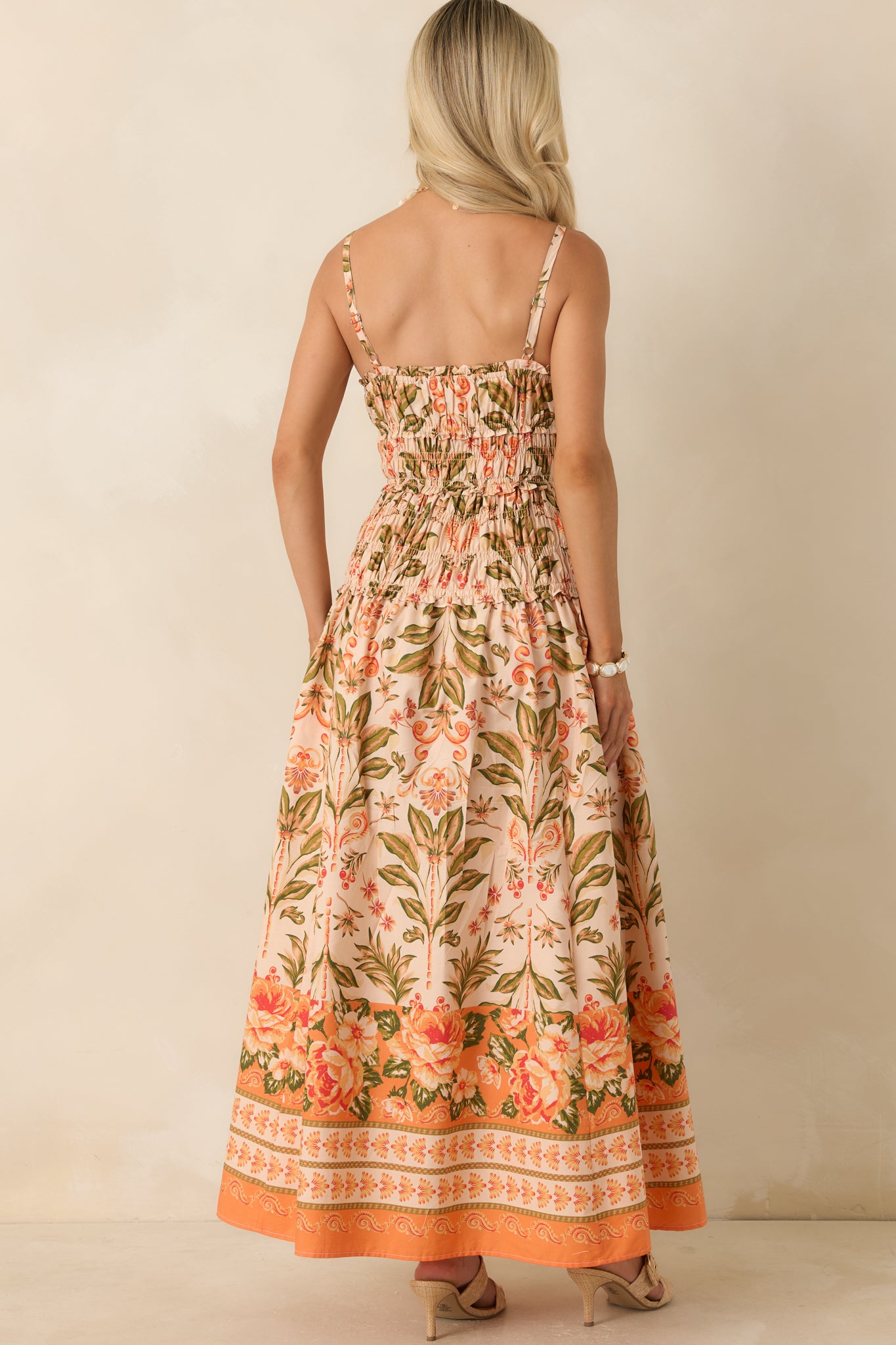 Rear view of the peach floral maxi dress featuring a fully smocked bodice, adjustable shoulder straps, and a flowing tiered skirt.