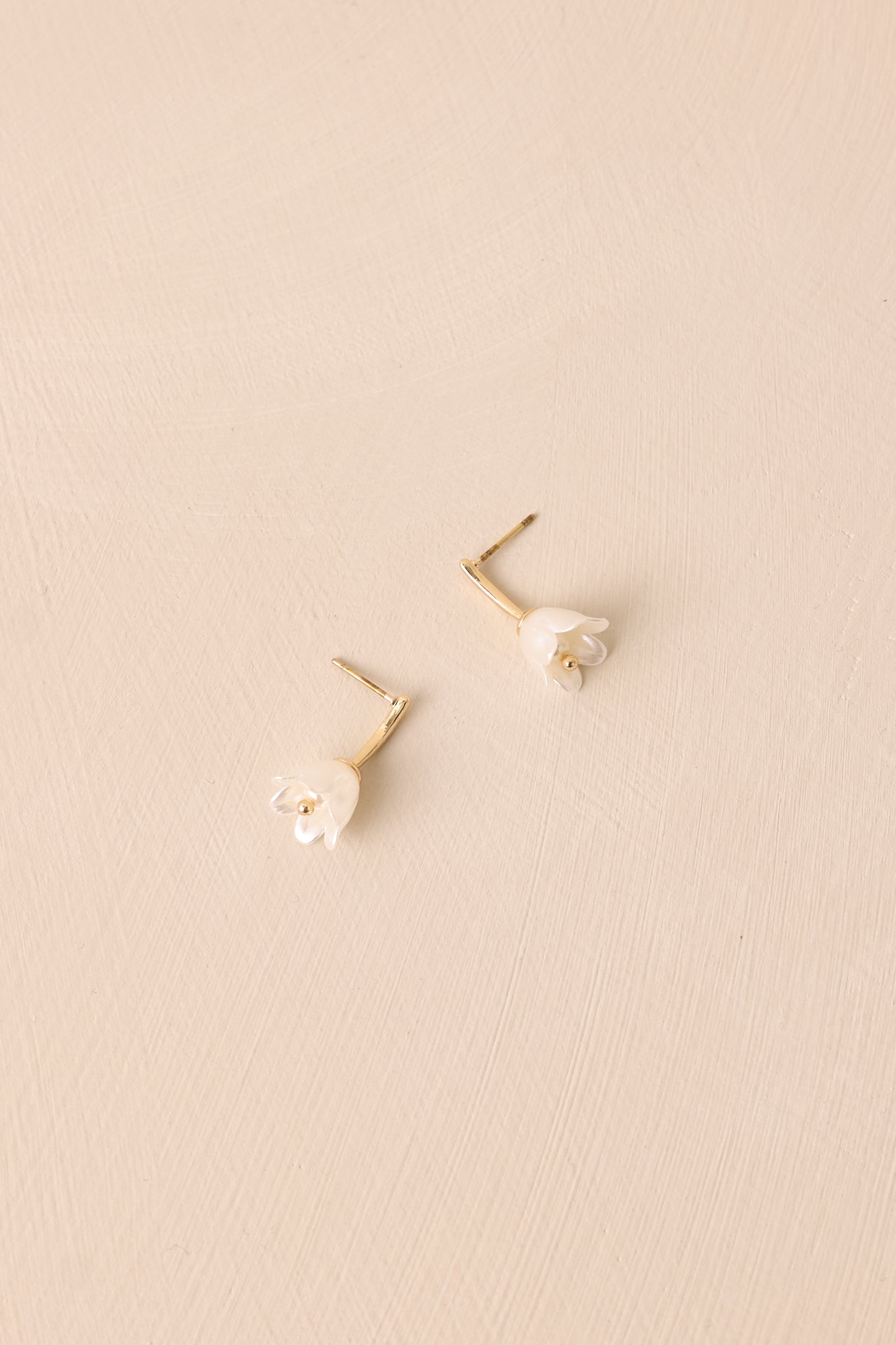 A close-up view of the stud earring design, showcasing the delicate gold hardware and pearlescent flower detail.