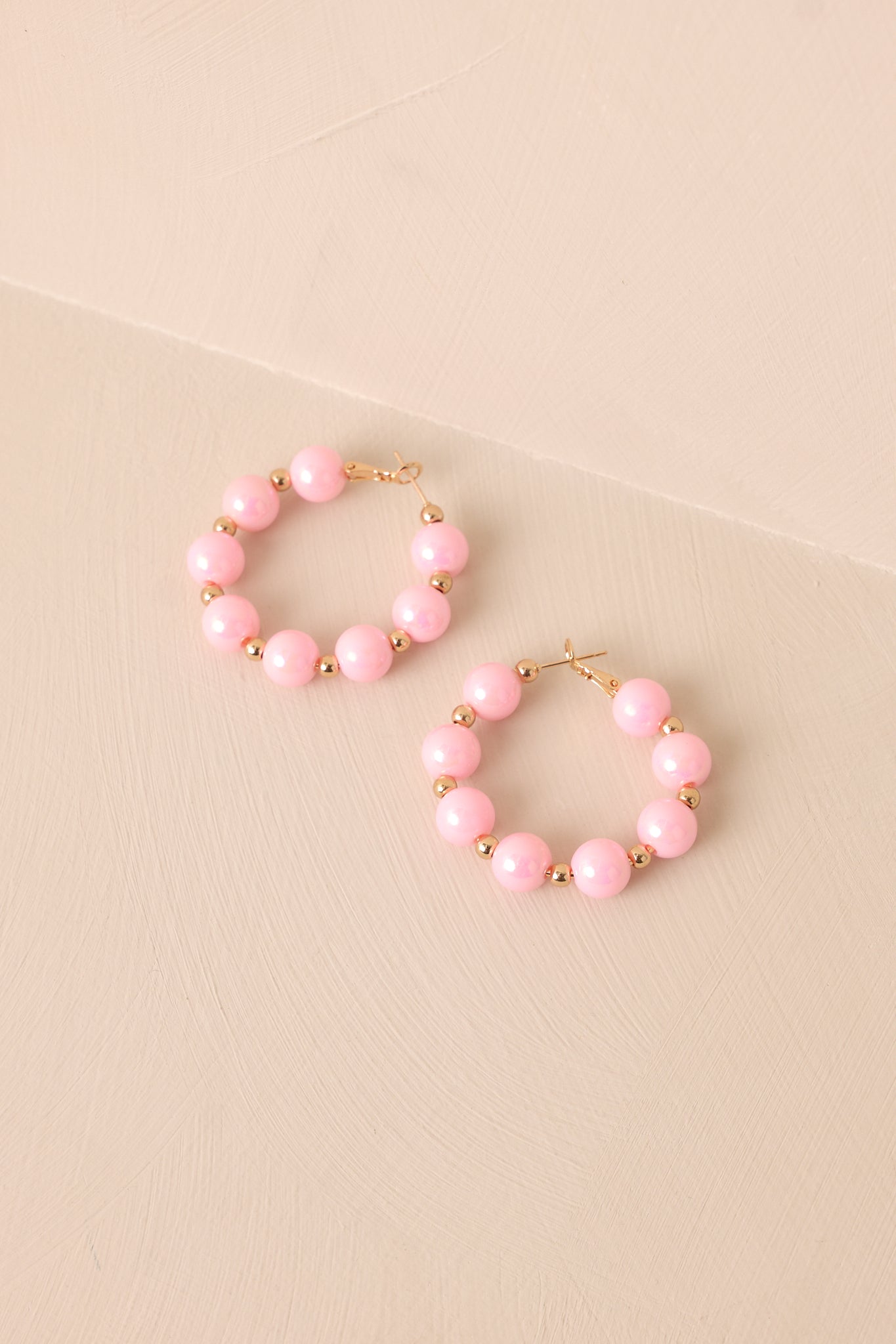 Soft pink pearlescent beads and dainty gold accents create a beautifully balanced design on this classic gold hoop earring.