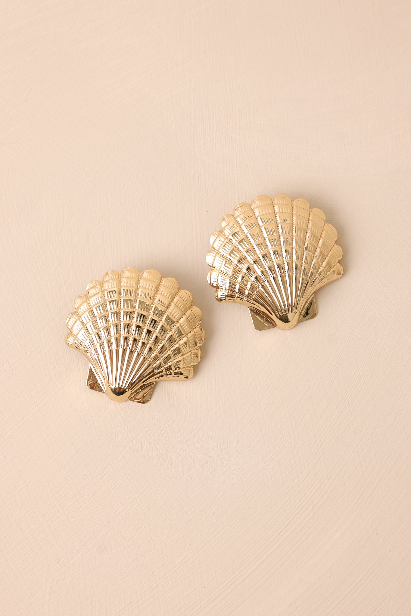 Gold earrings designed as large textured sea scallop seashells, offering a bold yet elegant coastal-inspired look.