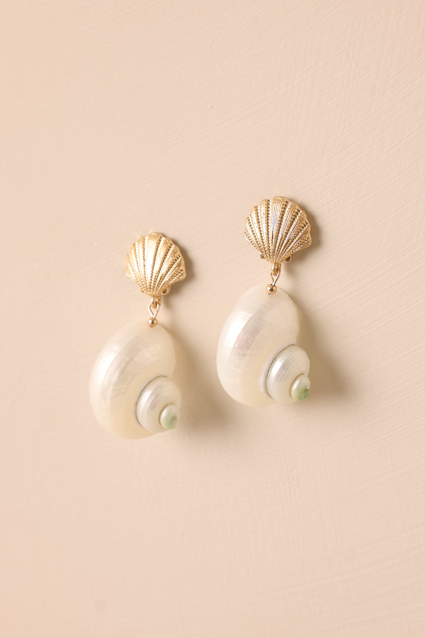 Angled shot of the earrings emphasizing the detailed textures on the shell stud and the contrasting green tip on the pearlescent shell.