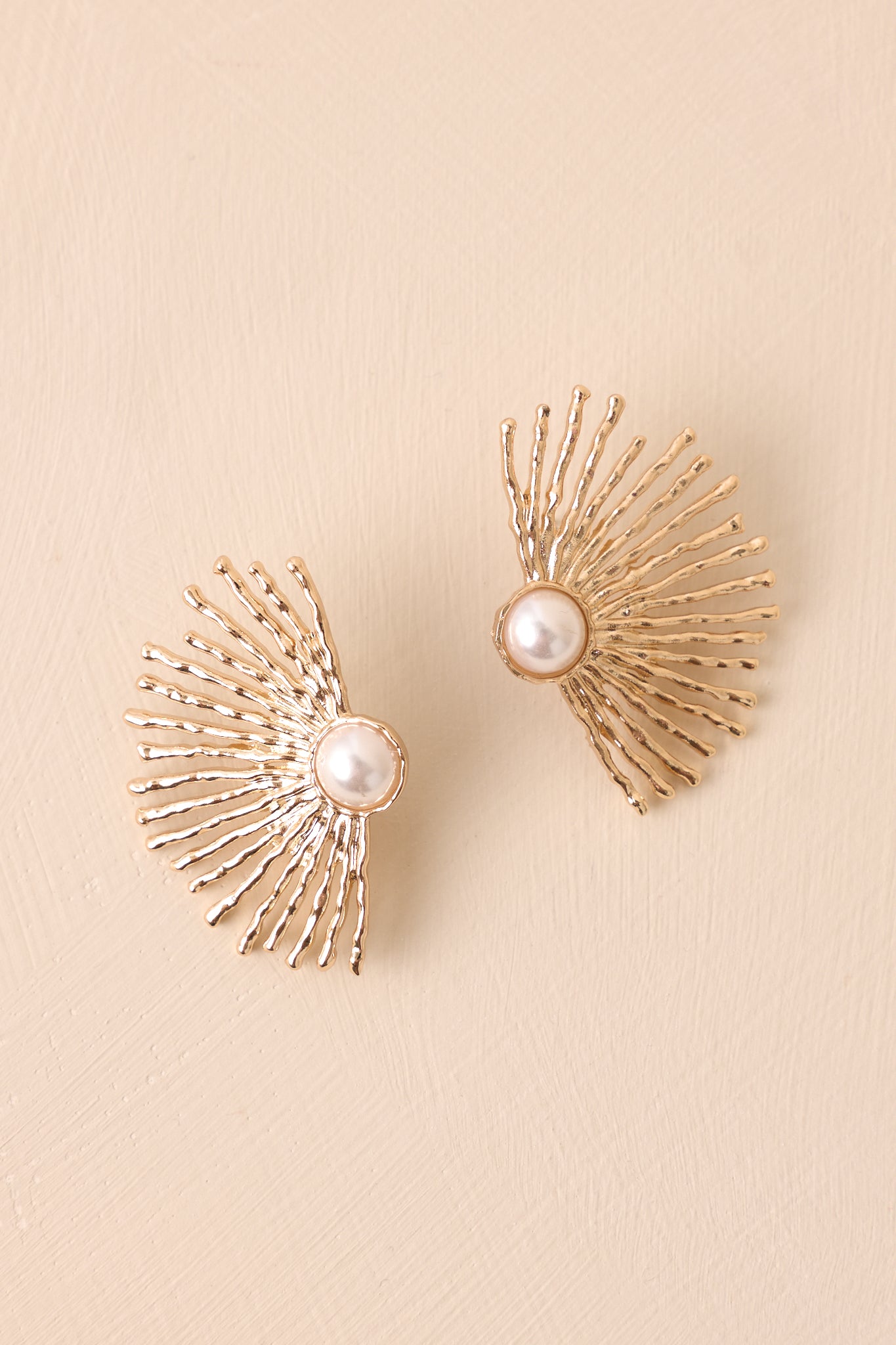 The intricate gold bezel frame surrounds the luminous ivory pearl, adding a touch of sophistication to these statement earrings.