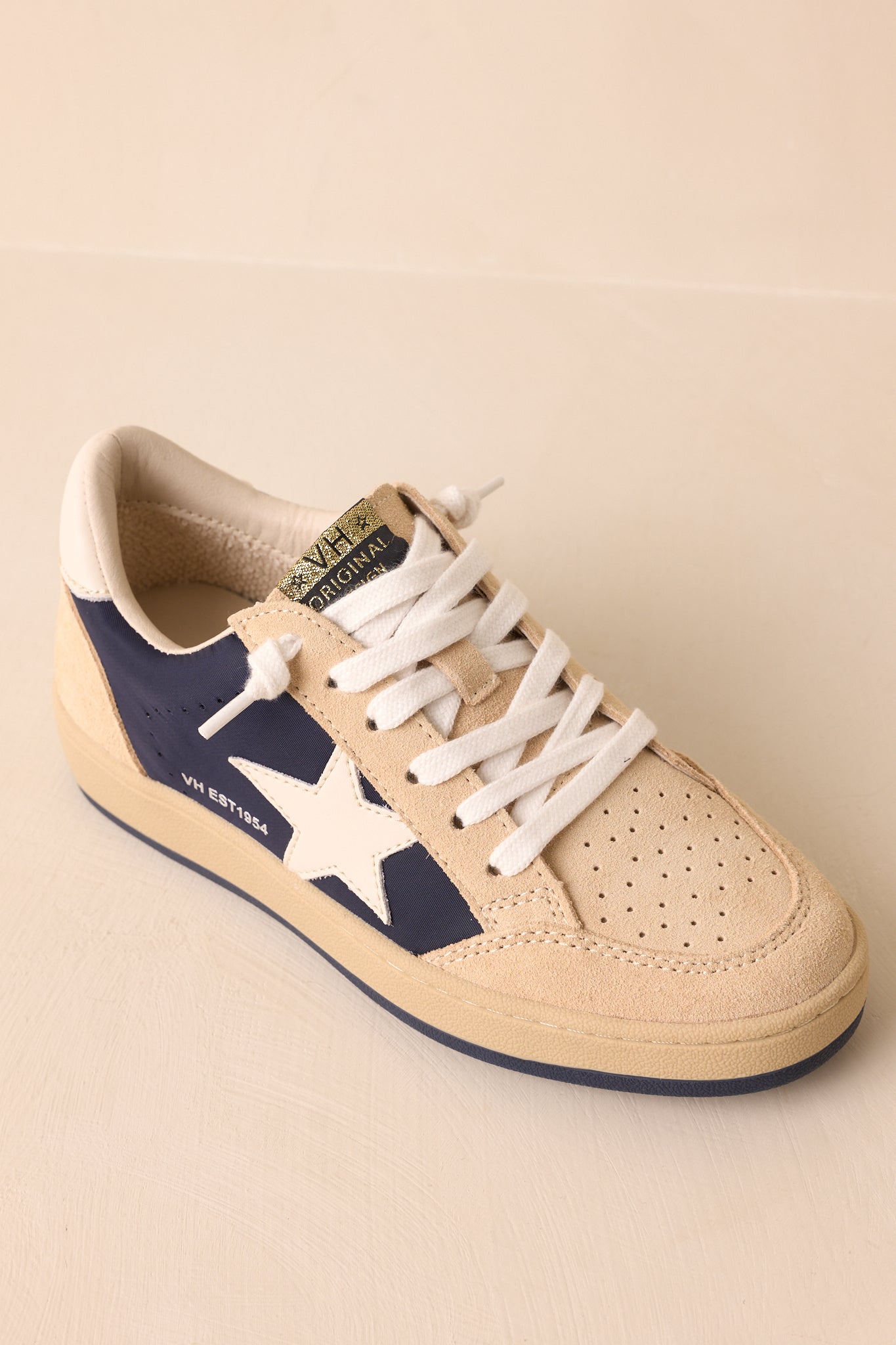 Top-down angled view emphasizing the lace-up front, gold logo tongue tab, and padded collar opening.