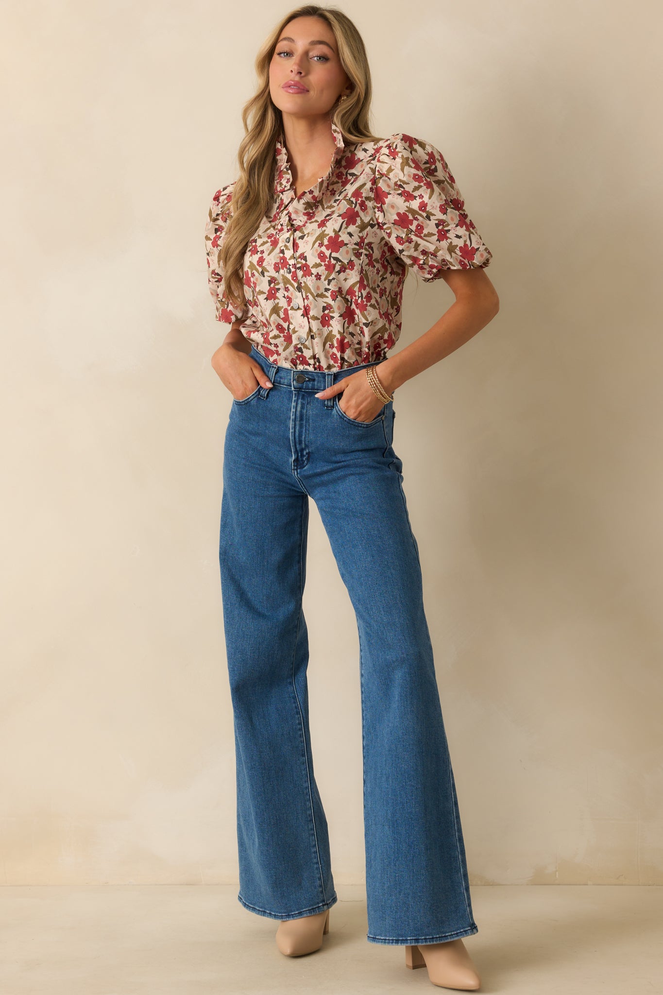 A full view of the beige ecru top with a red floral print, showing the ruffled collar neckline and button front.