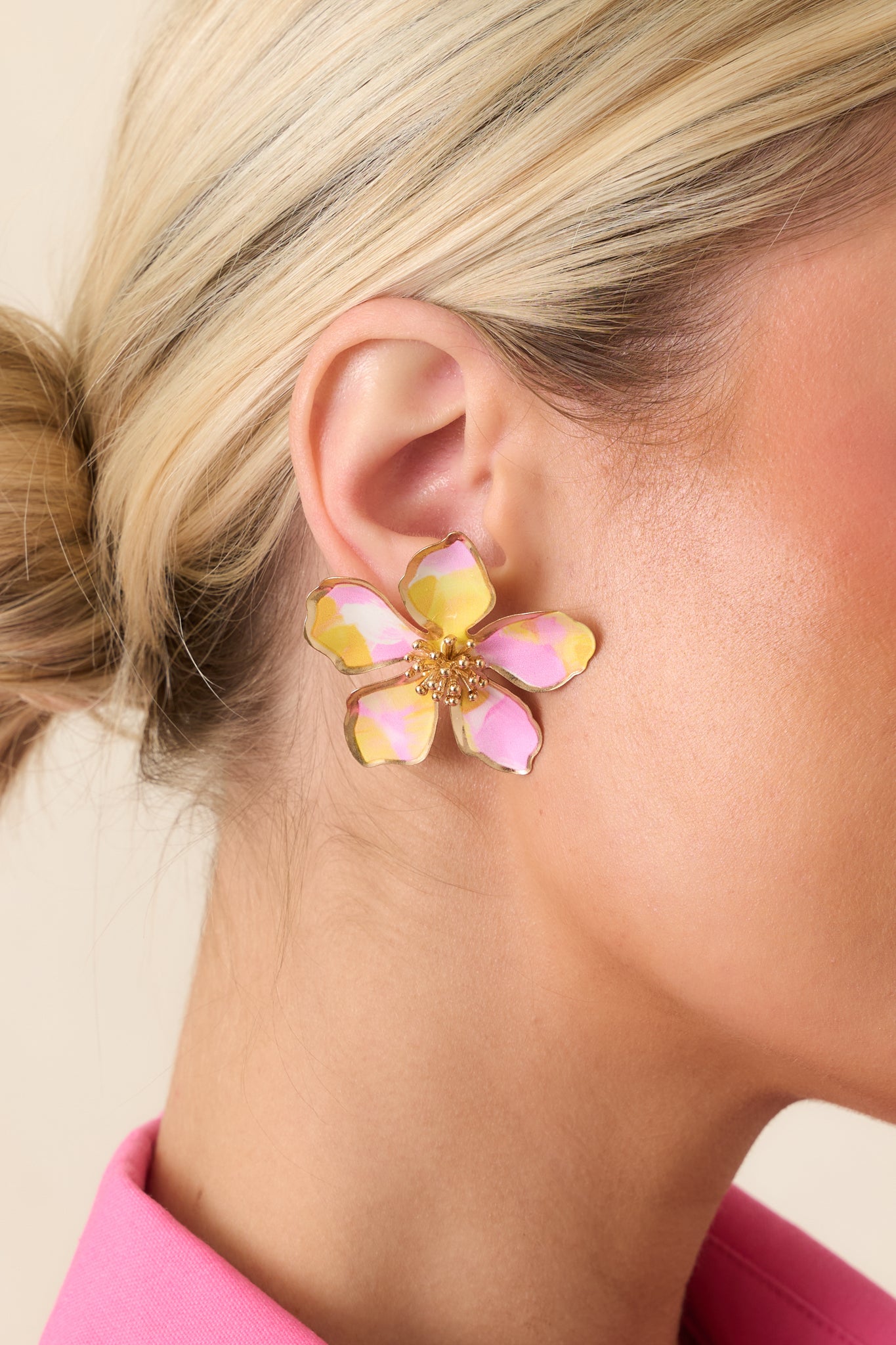 Close-up of pink and yellow floral stud earrings highlighting the sculpted oversized petals, glossy finish, and textured center.