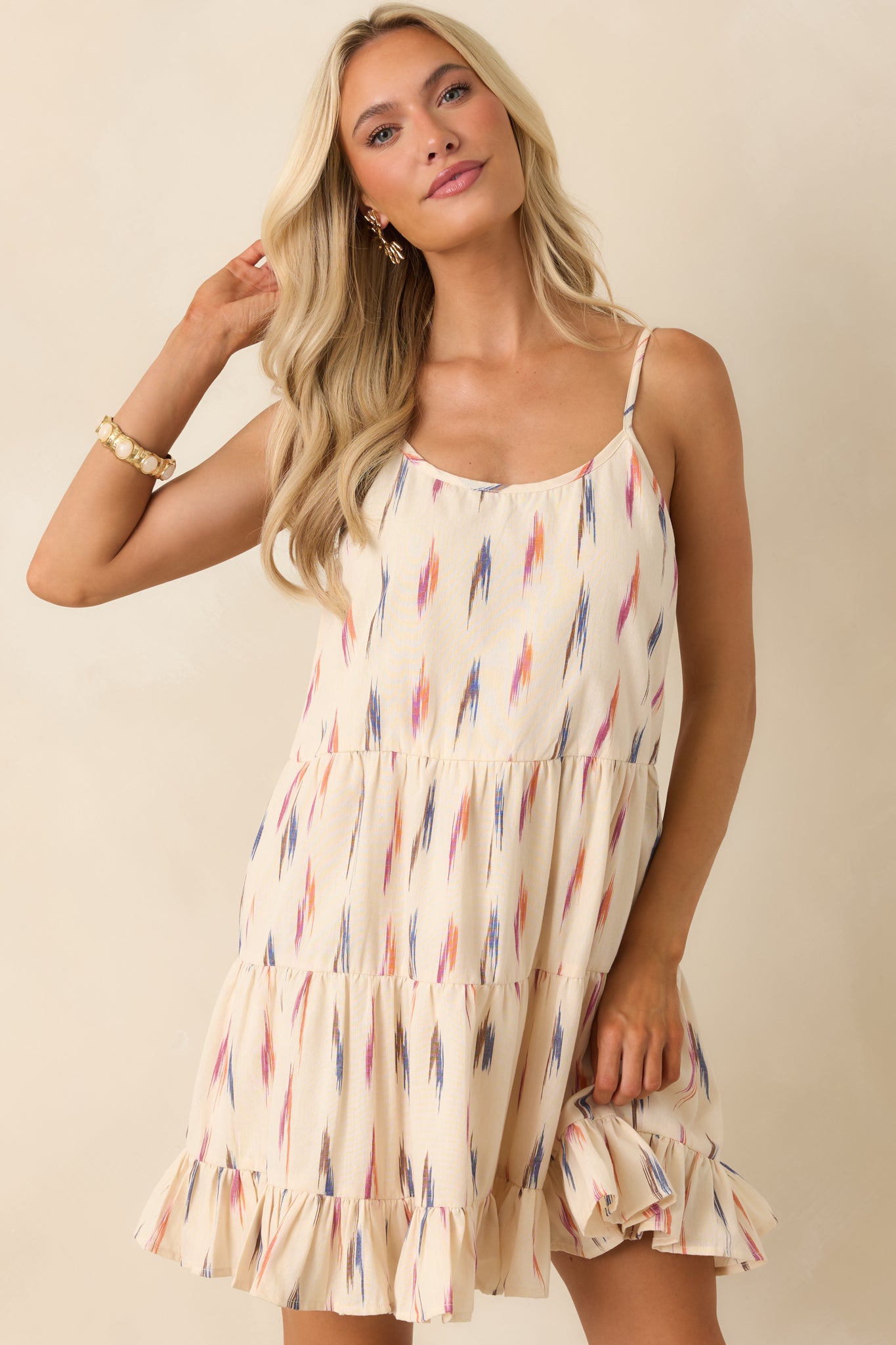 Detailed look at the tiered construction and ruffled hem of the ivory printed mini dress.