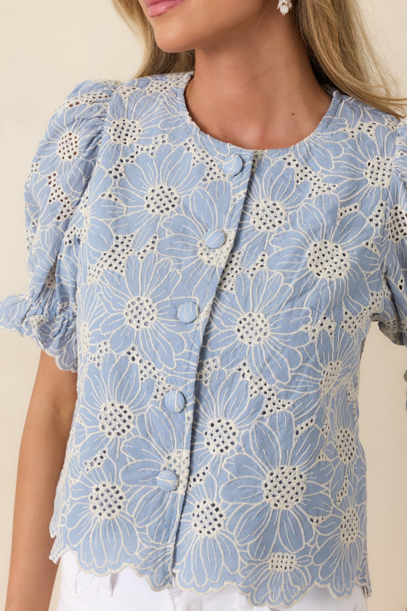 Close view of floral embroidery and eyelet detailing on soft fabric.