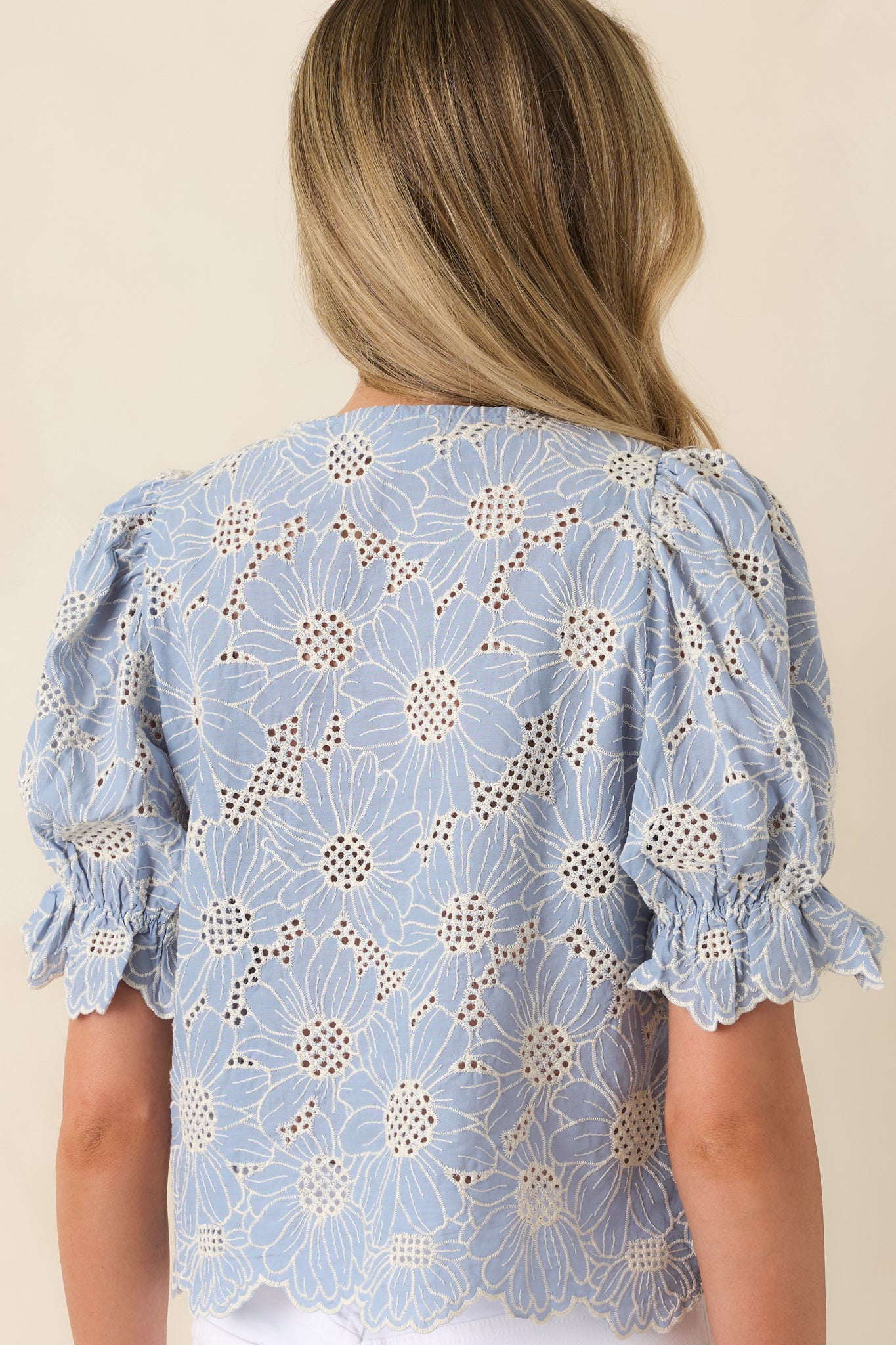 Rear view of top with puff sleeves, scalloped hemline, and embroidered texture.