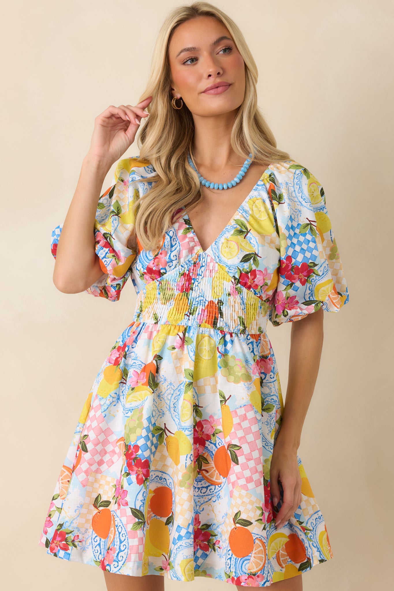 Smocked empire waist detail on a citrus print mini dress showing soft gathered texture and flexible stretch.