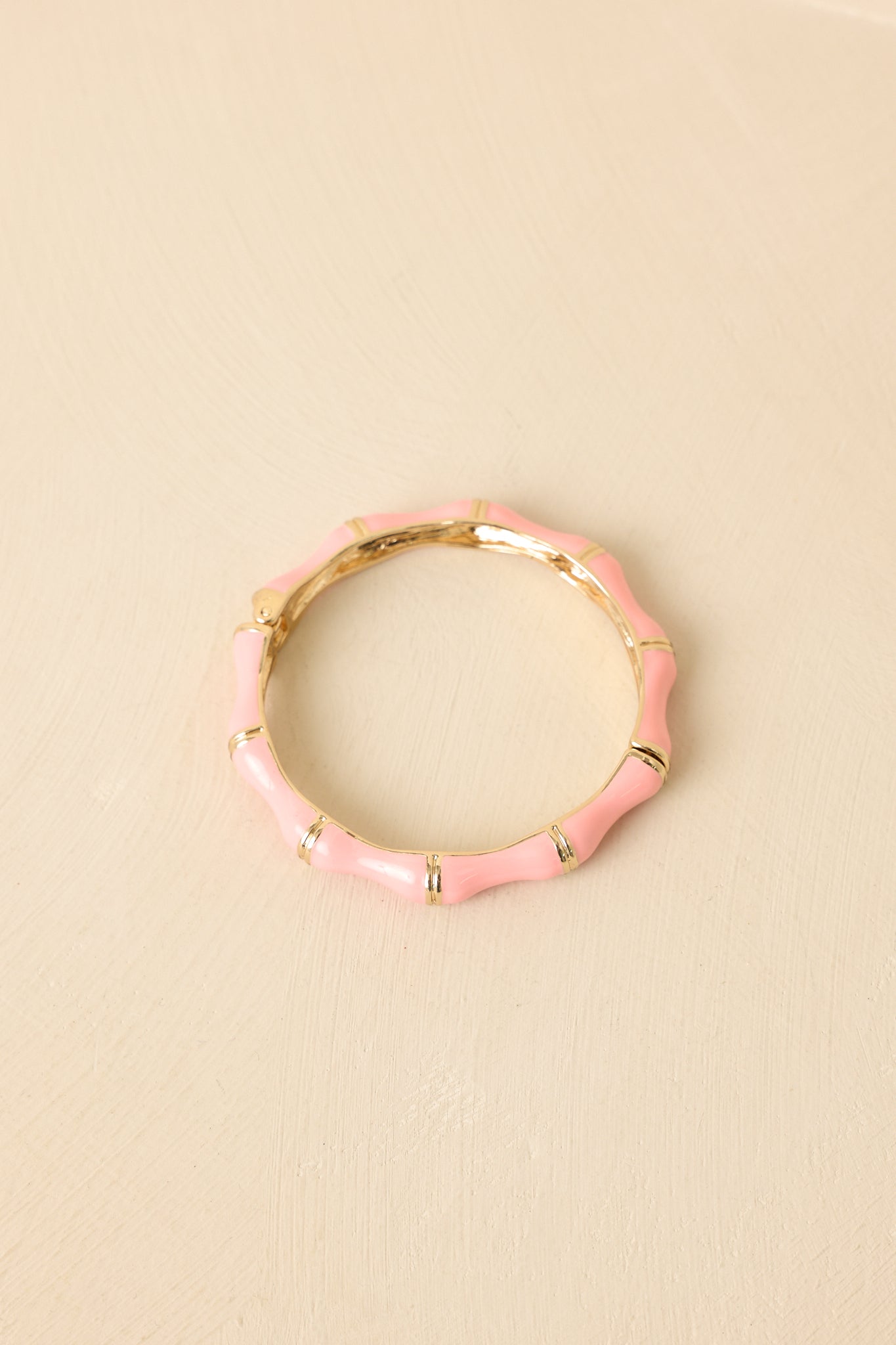 Angled view of enamel bracelet on beige backdrop highlighting smooth surface and structured design.