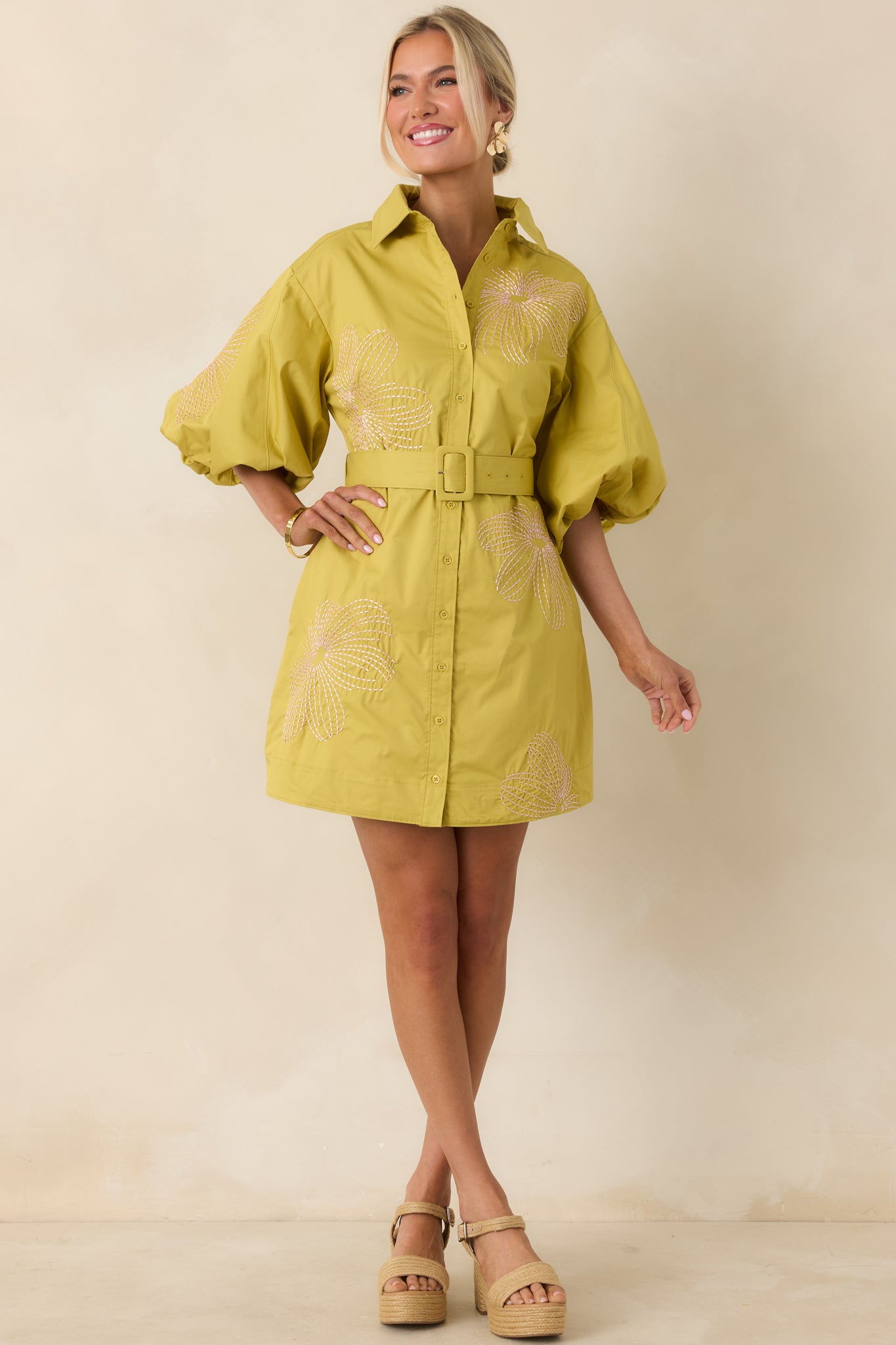 Feminine cotton mini dress with puff sleeves, contrast pink embroidery, and a defined belted fit.