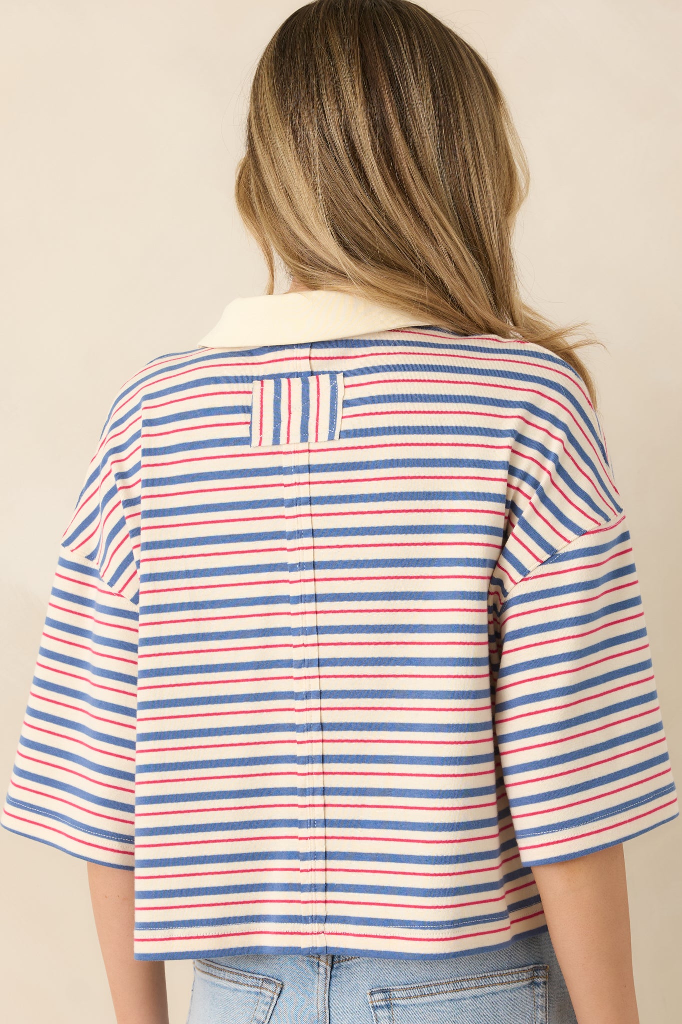 Rear view of the blue multi-stripe top displaying short sleeves and relaxed boxy silhouette.