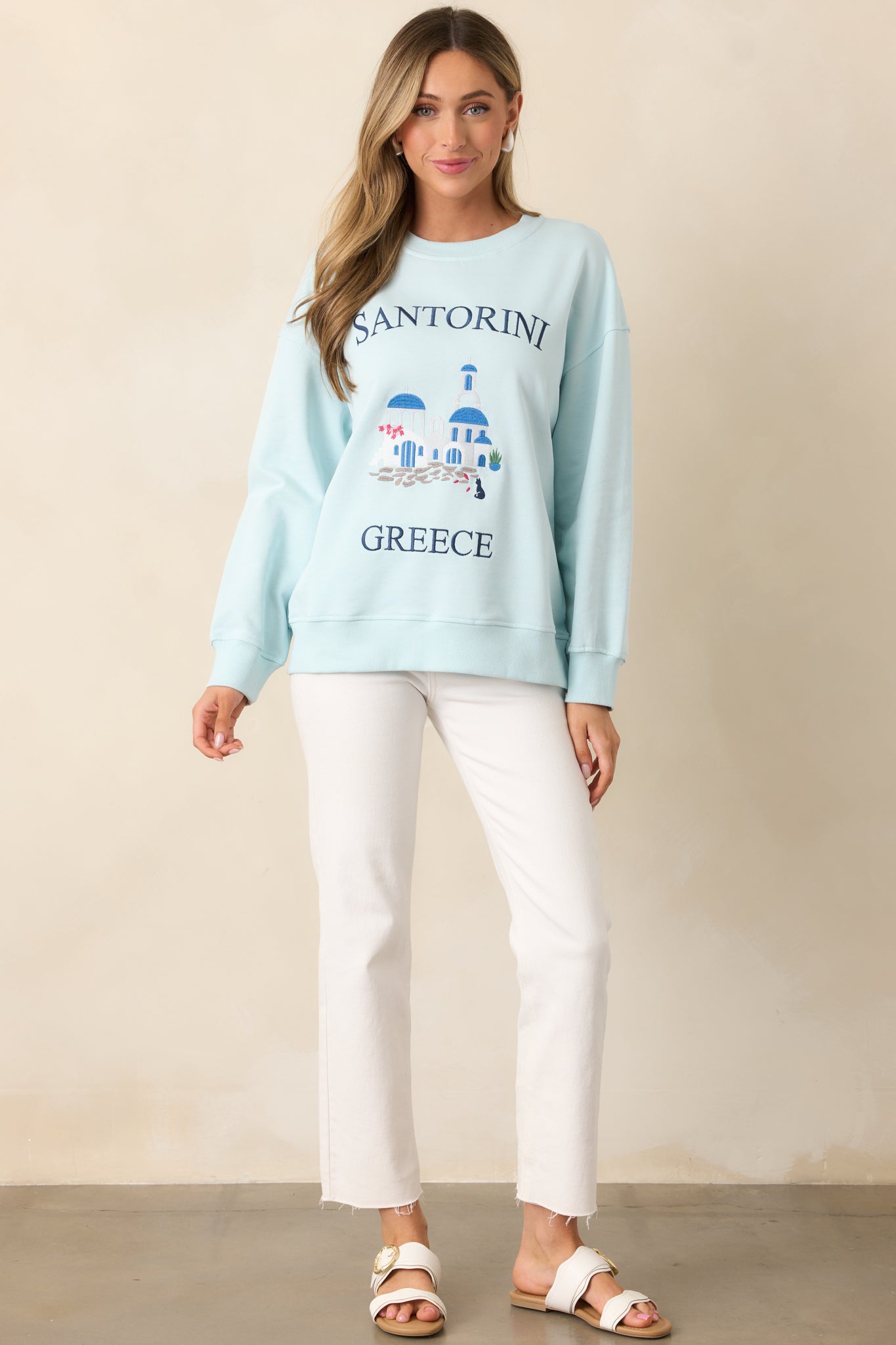 A sweatshirt with a rounded crew neckline, long sleeves, and a Santorini Greece embroidered design on the front.