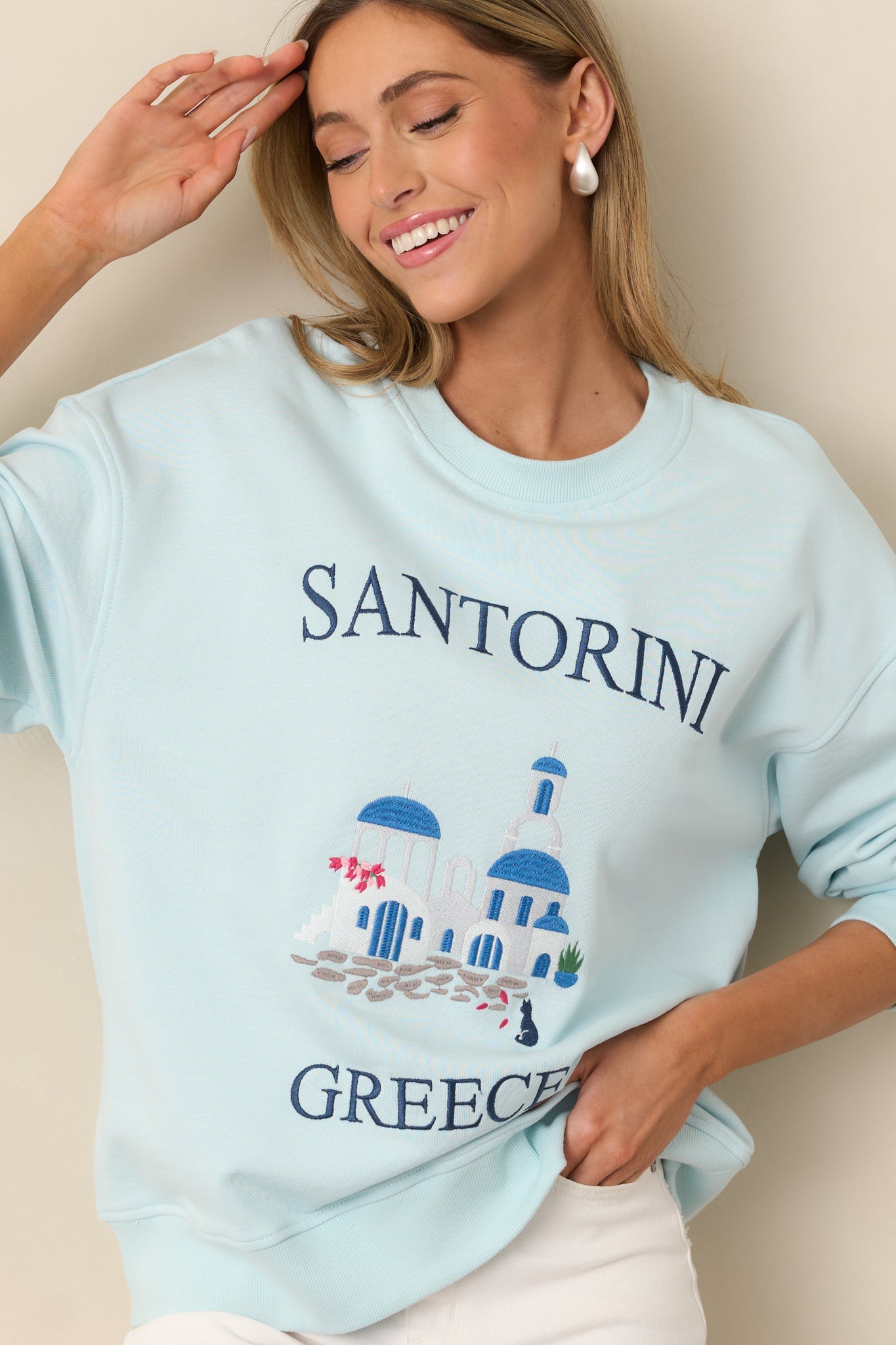 A partial view of the sweatshirt, highlighting the detailed Santorini Greece embroidery.