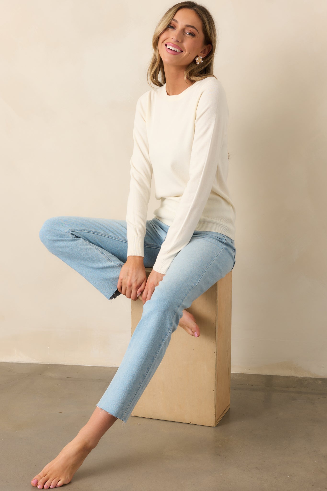 Classic ivory sweater with a relaxed fit, ribbed hems, and a rounded crew neckline—an effortlessly cozy essential.