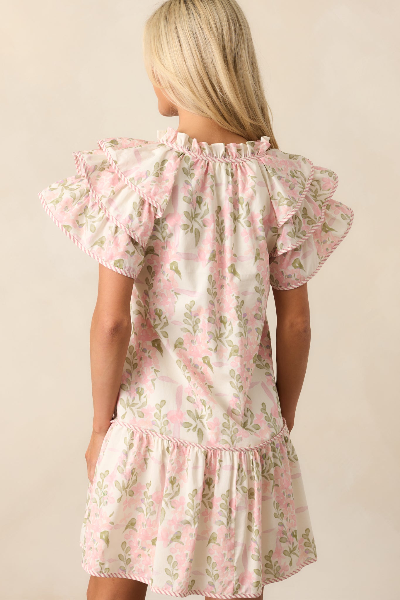 Back view of the pink mini dress featuring the soft flutter sleeves and relaxed fit, with the ruffle neckline detail visible at the back.