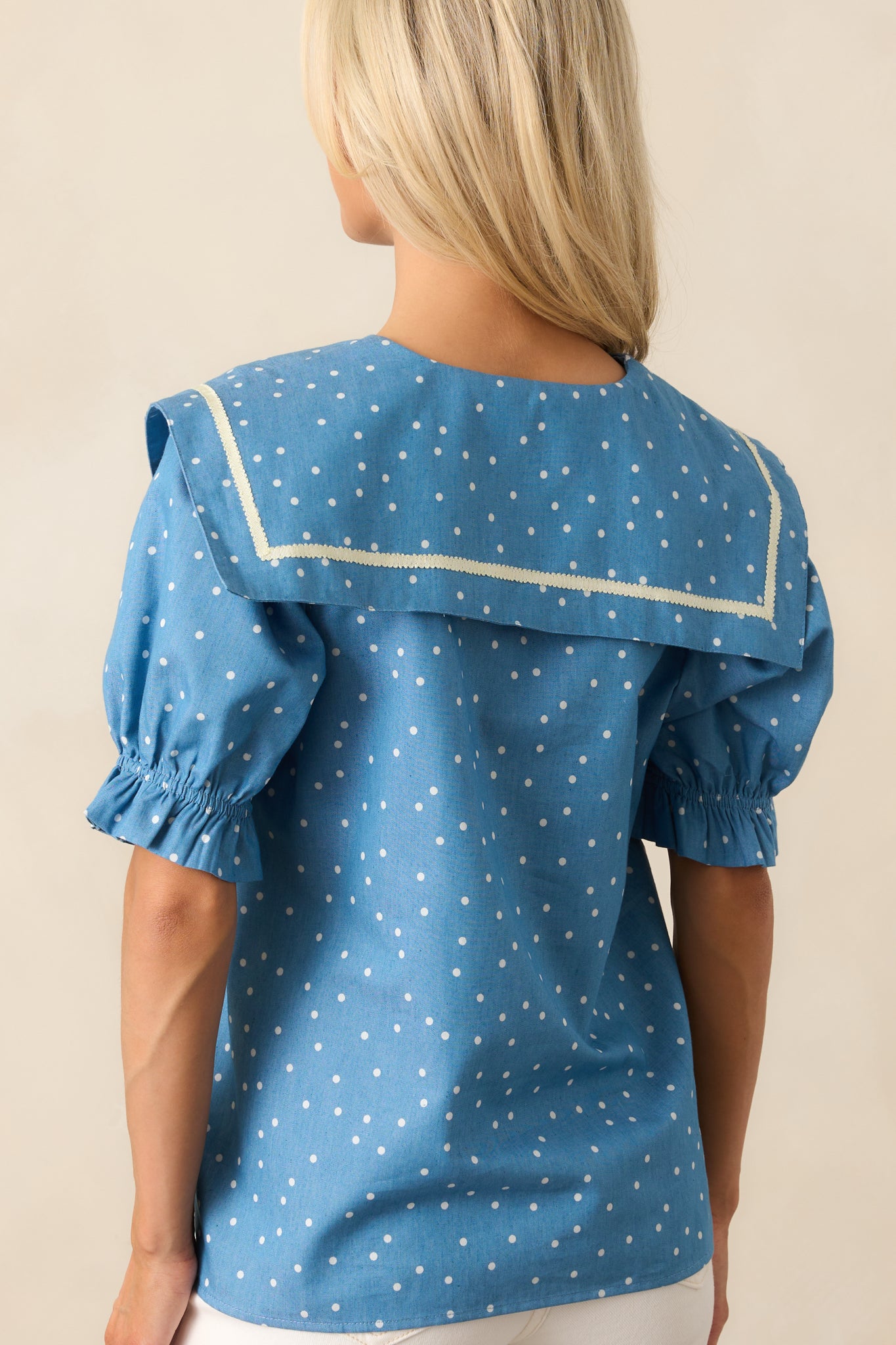 A view from behind of the chambray top, showcasing the continued polka dot design and gently gathered sleeves.