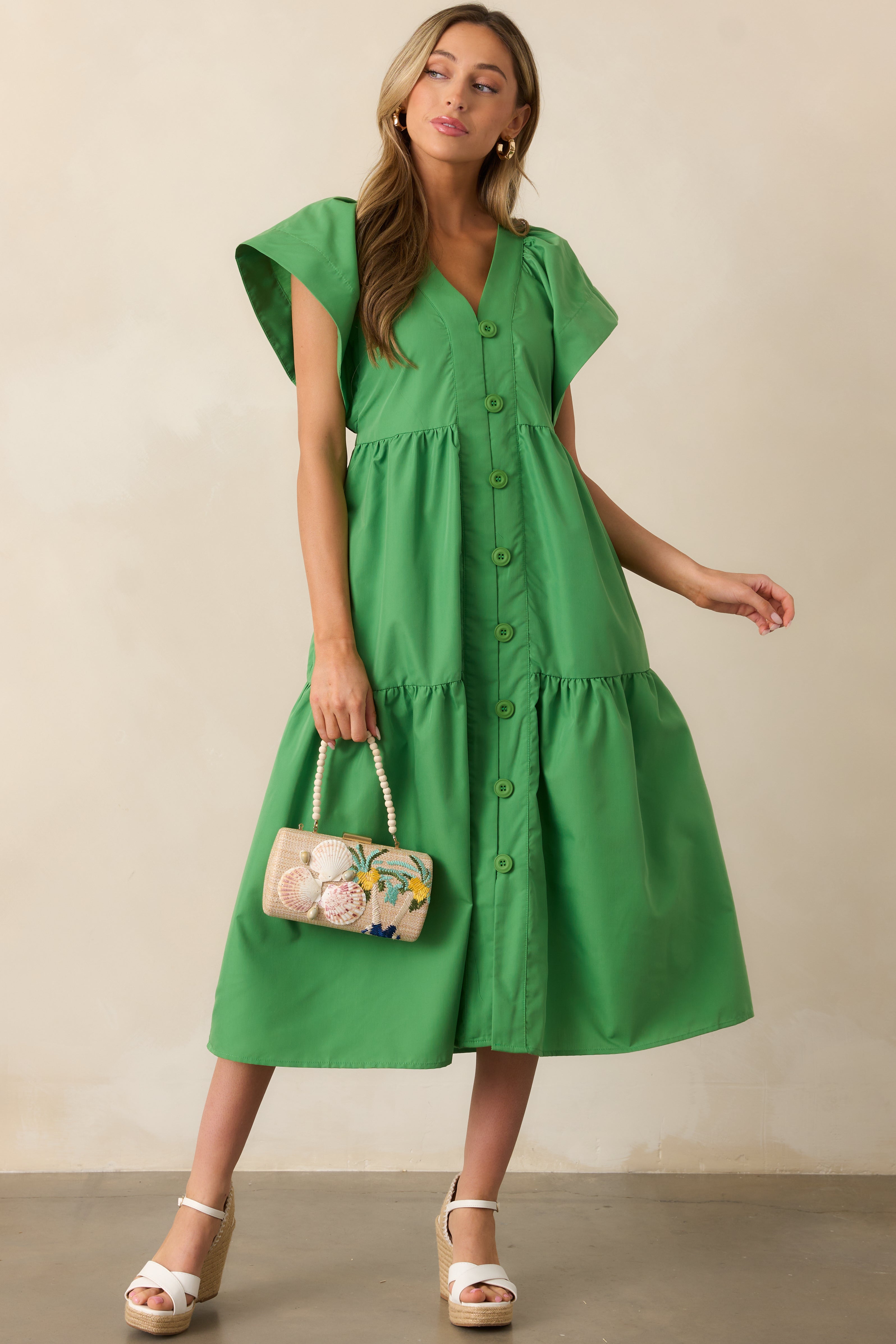 A slightly angled front view showcasing the short flutter sleeves and the flowy tiered design of the green midi dress.