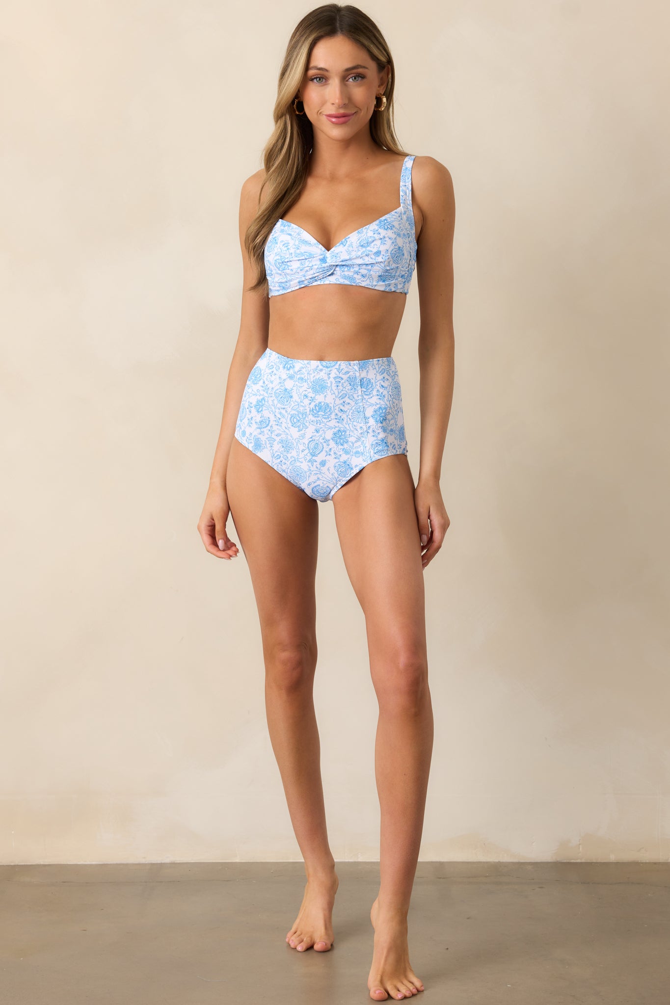 A stylish ivory bikini top with a delicate blue floral pattern, showcasing its supportive rounded cups and adjustable straps.
