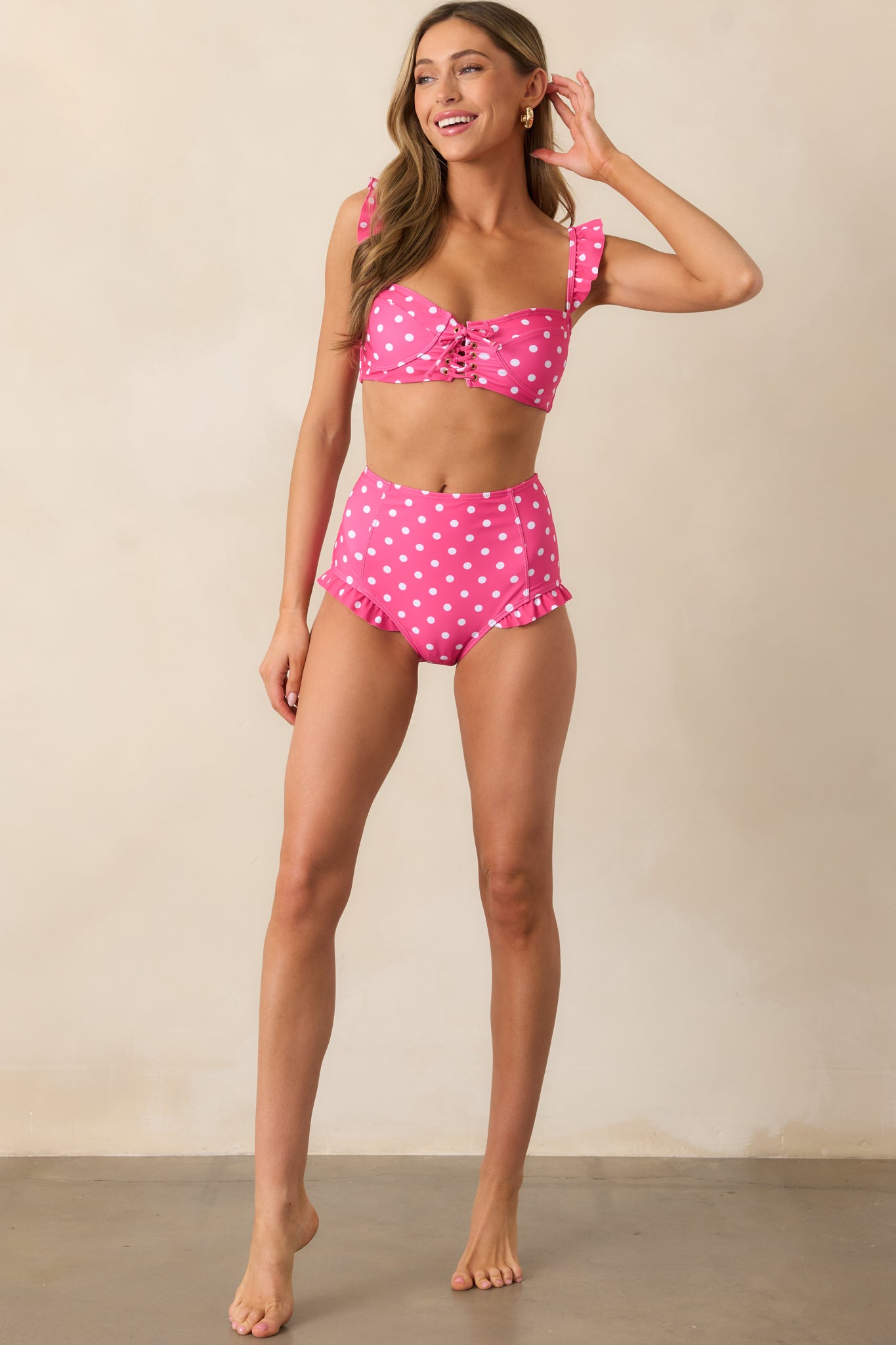 A view of the pink bikini top with white polka dots, showcasing the adjustable lace-up front, ruffled shoulder straps, and removable padding for a comfortable, flattering fit.