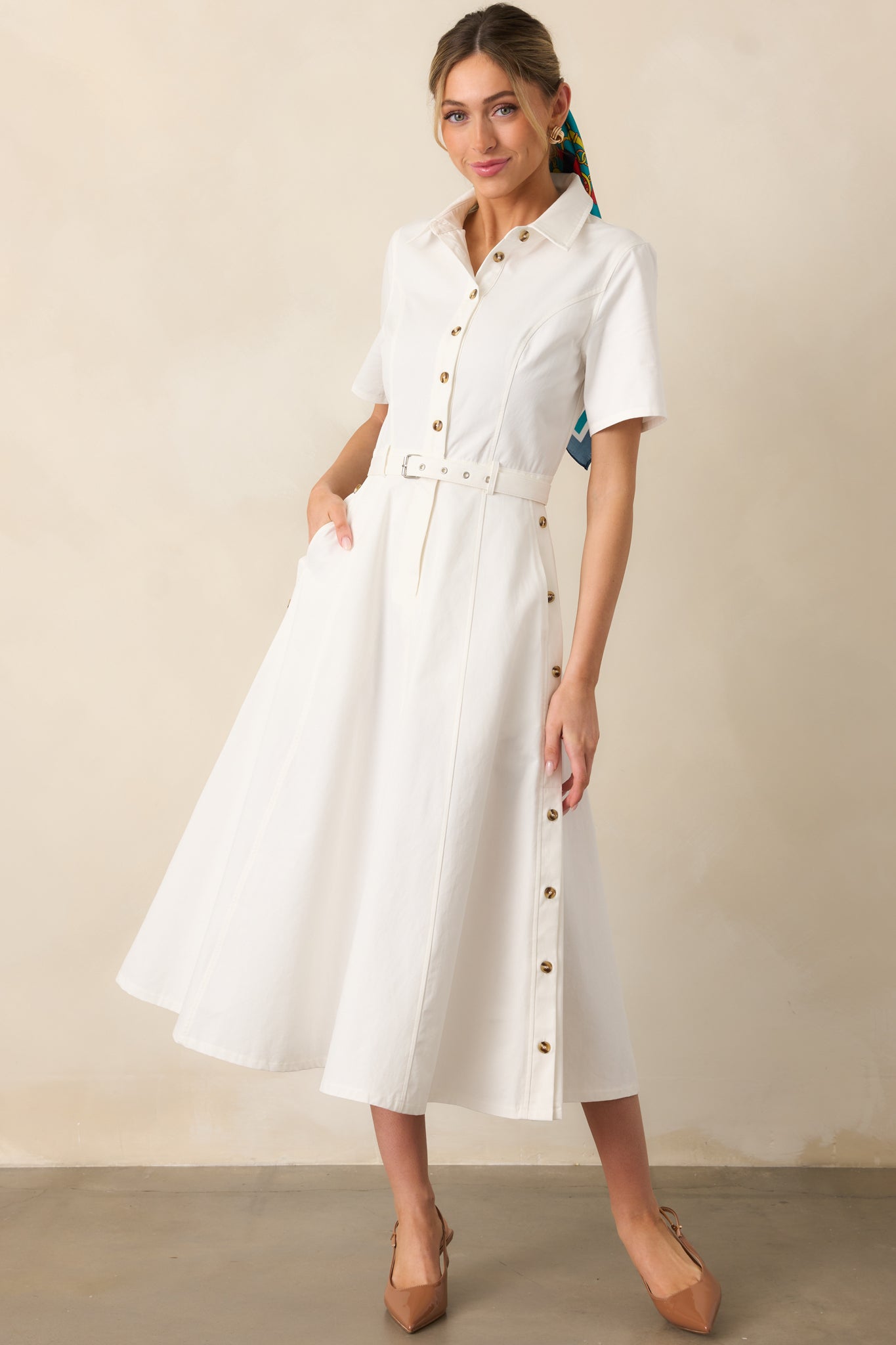 Functional pockets and decorative side buttons add charm to this collared white dress, designed for both style and practicality.