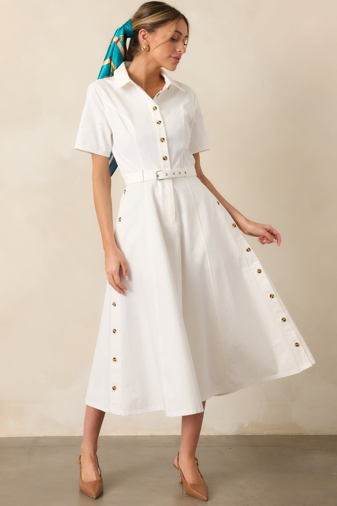 A white dress with a collared neckline, functional button front, and a removable matching belt for a polished and versatile look.