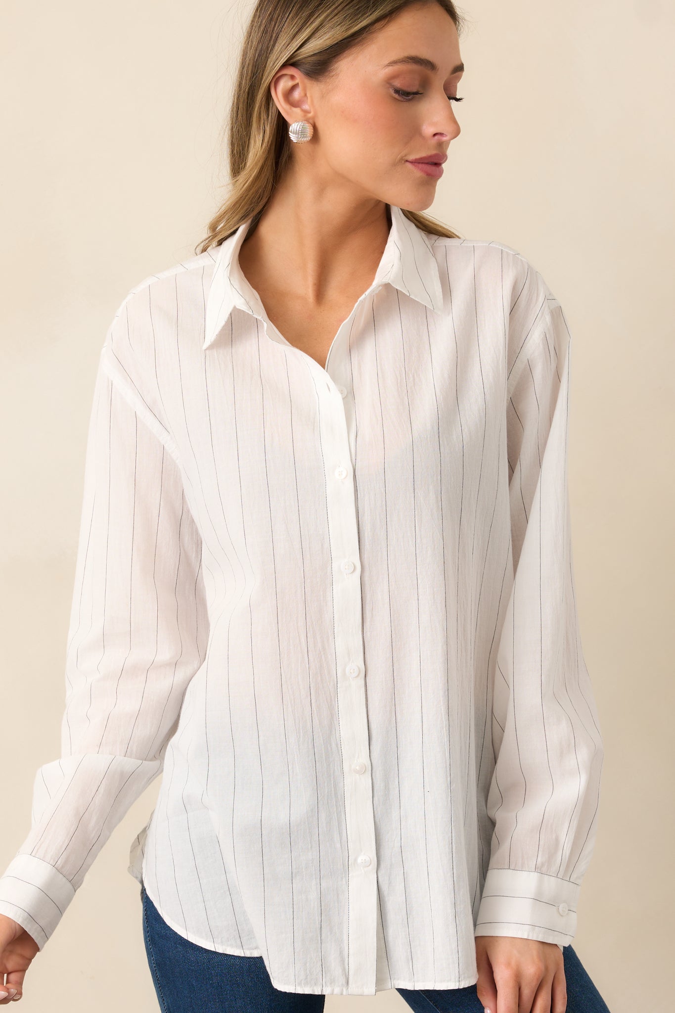The white shirt displayed from head to hip, emphasizing its long sleeves with button cuffs and structured silhouette.