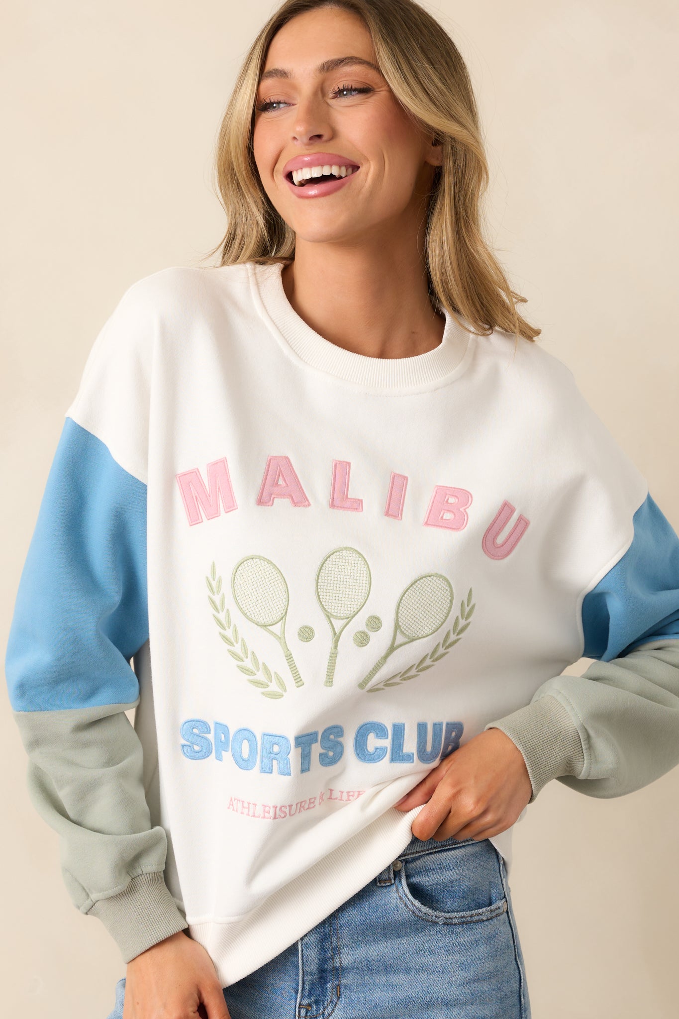 The "Malibu Sports Club" embroidery on the front stands out against the clean white fabric and soft colorblocked sleeves.