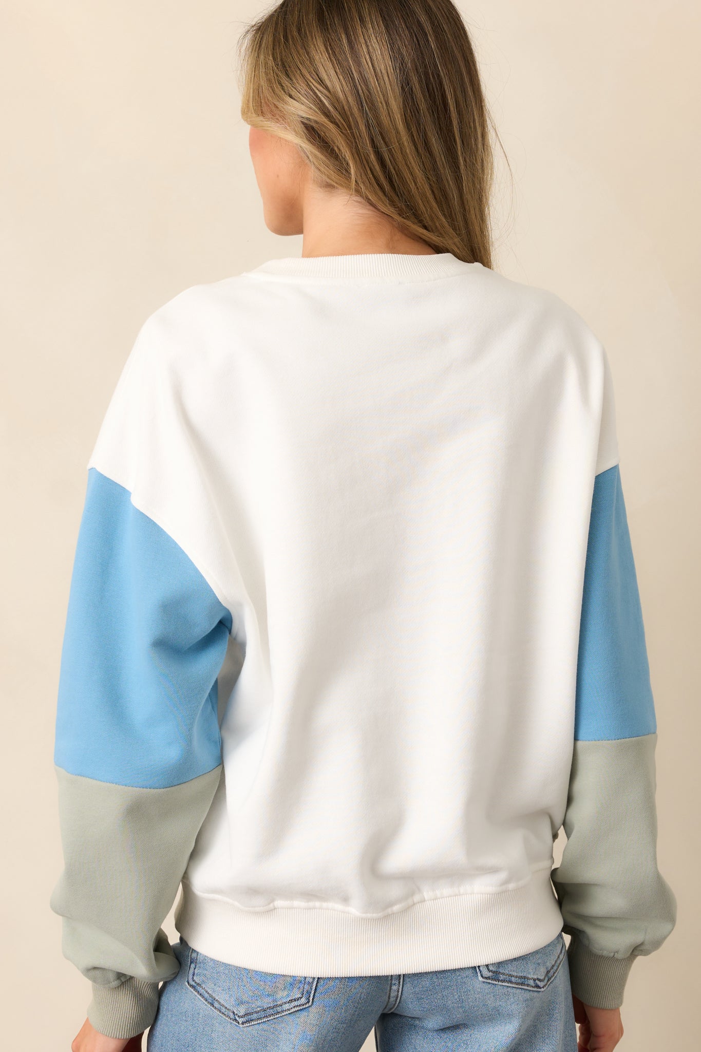 The back of this white sweatshirt maintains its simple design, with no additional details beyond the clean, colorblocked sleeves.
