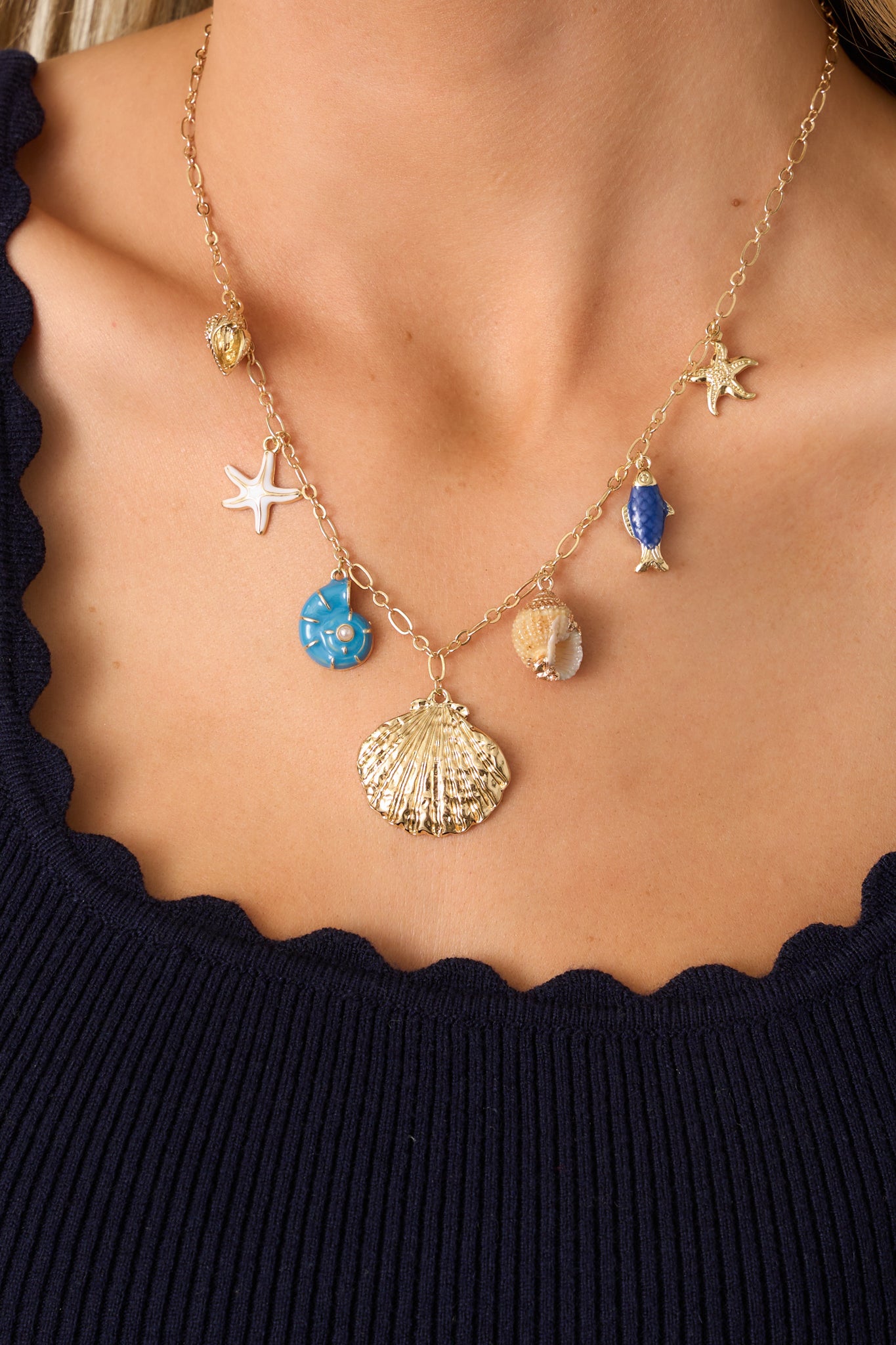 A zoomed-in look at the necklace’s seashell pendants, emphasizing the mix of gold, white, and blue tones, along with the fine details of each charm.