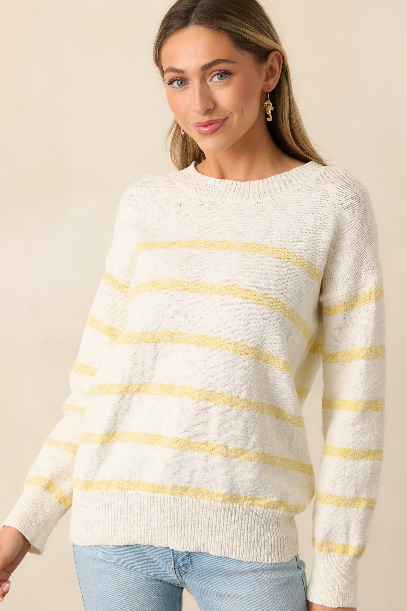 Cozy ivory sweater featuring a round neckline and ribbed hemlines for a classic touch.
