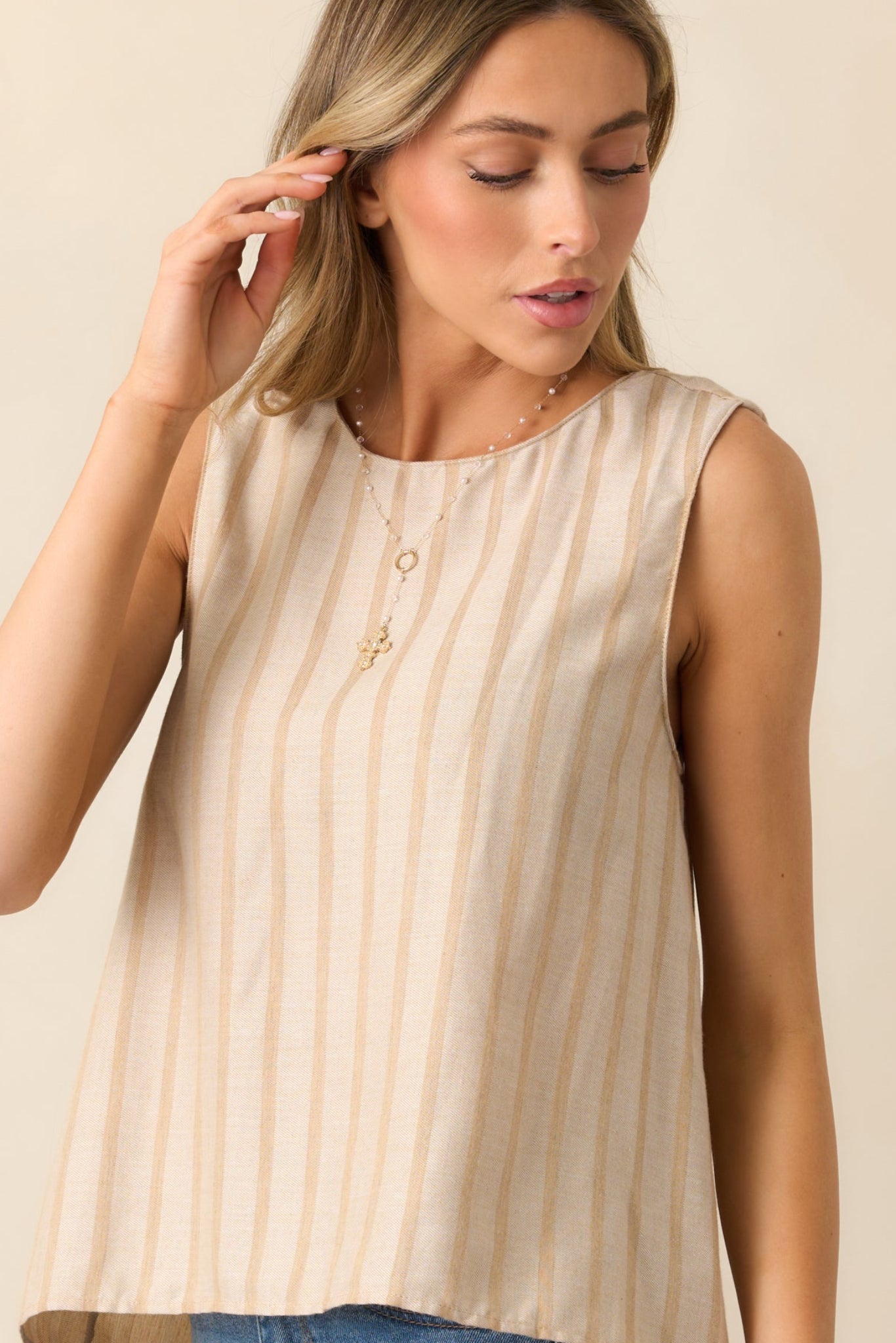 A detailed view of the sleeveless design, showcasing the soft lines and simple elegance of the beige top.