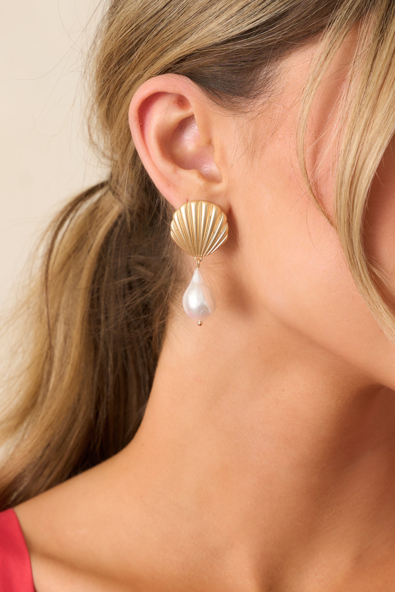 Gold drop earrings with a textured scallop seashell stud, an ivory faux pearl teardrop dangle, and gold jump rings connecting the two for a graceful, coastal-inspired design.