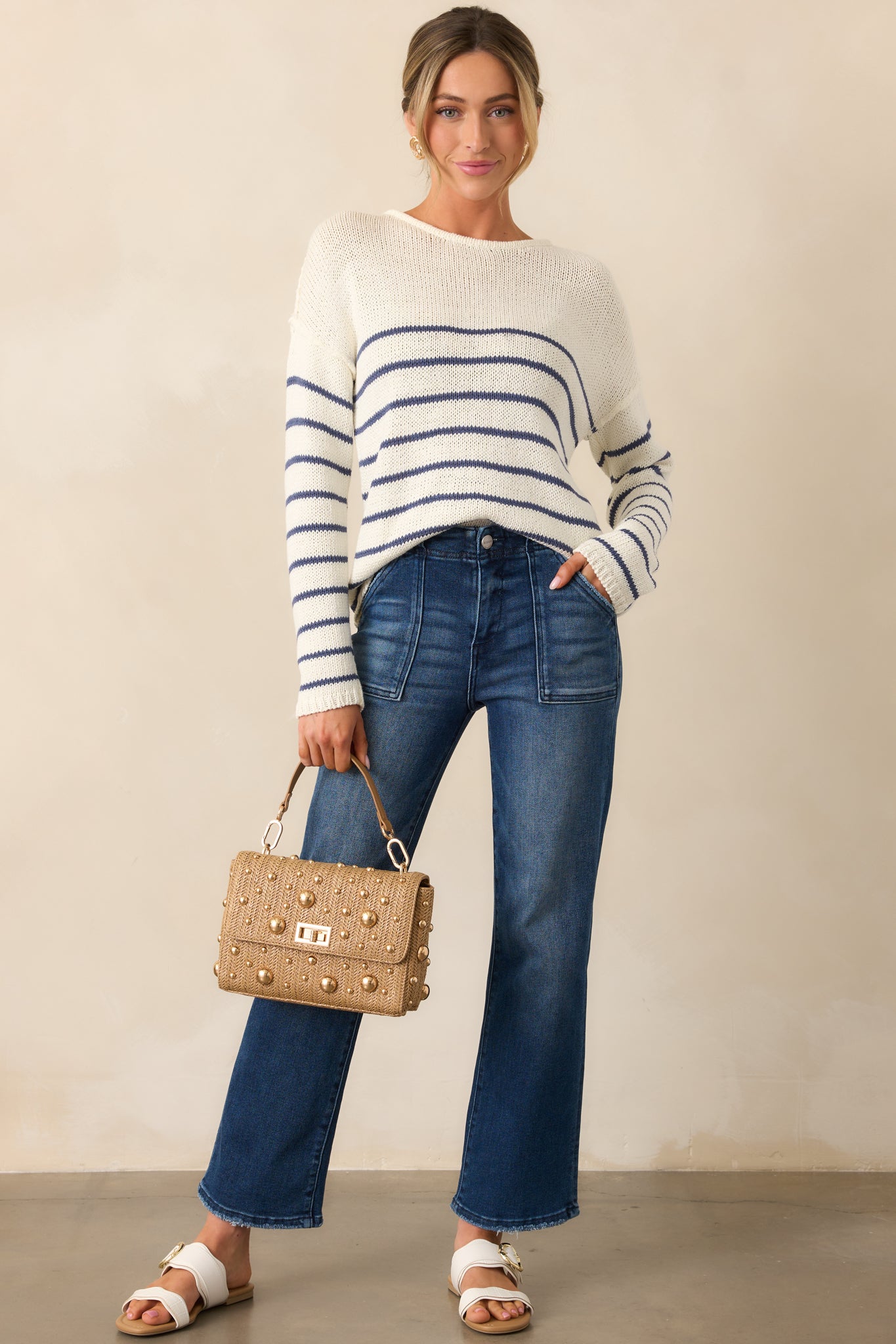 A cozy ivory sweater featuring navy stripes and reverse hem detailing on the sleeves for a modern touch.