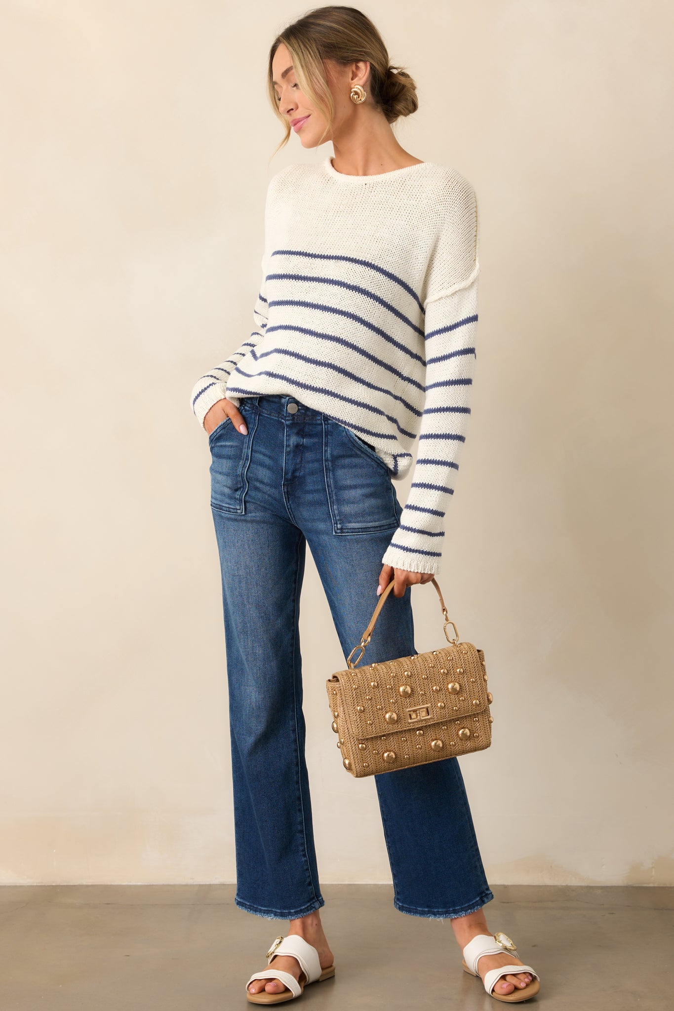 An ivory sweater with a rounded neckline, long sleeves, and navy stripe detailing along the body.