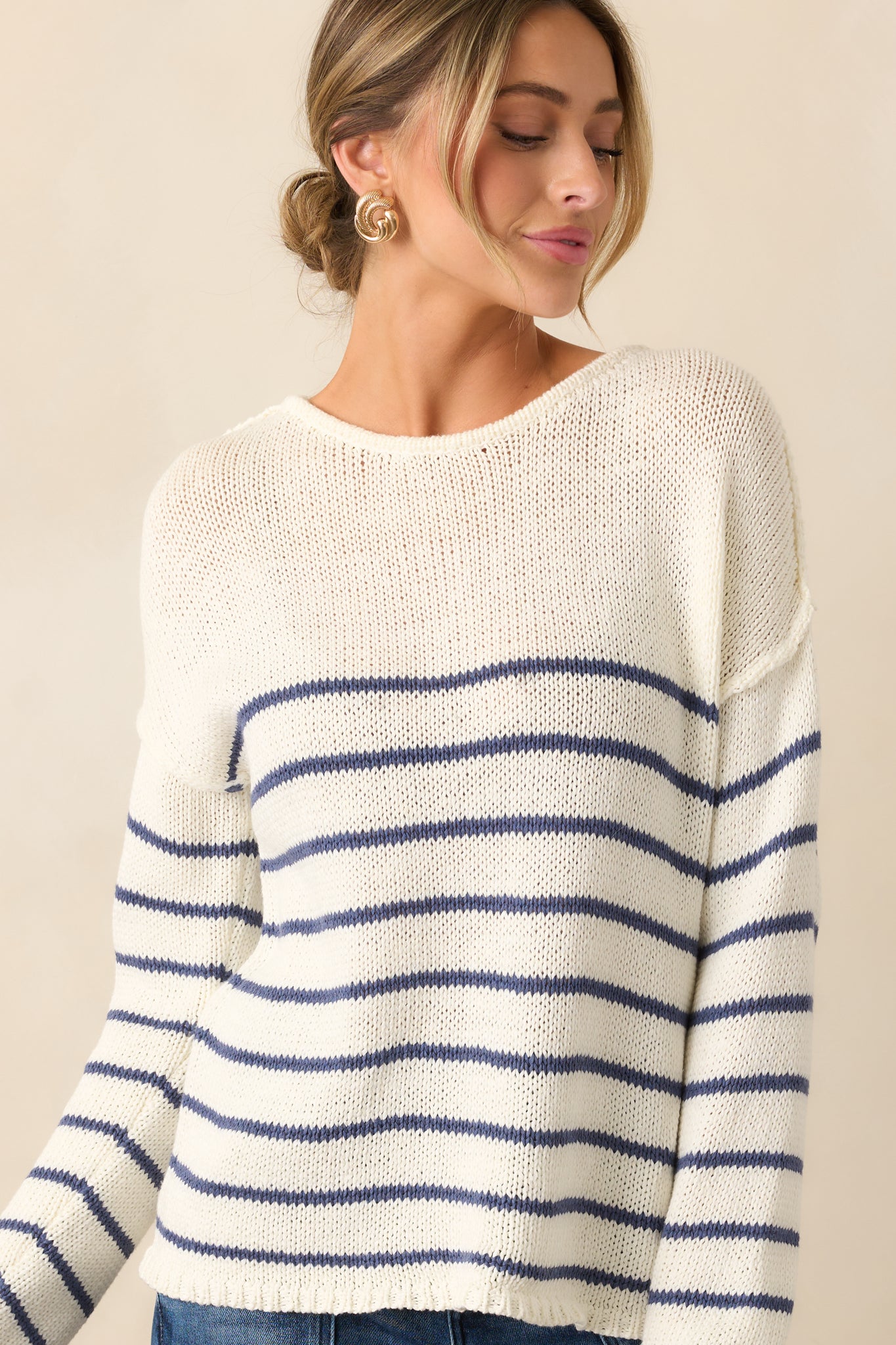 A partial shot focusing on the long sleeves and reverse hem detailing, showcasing the sweater’s unique design.