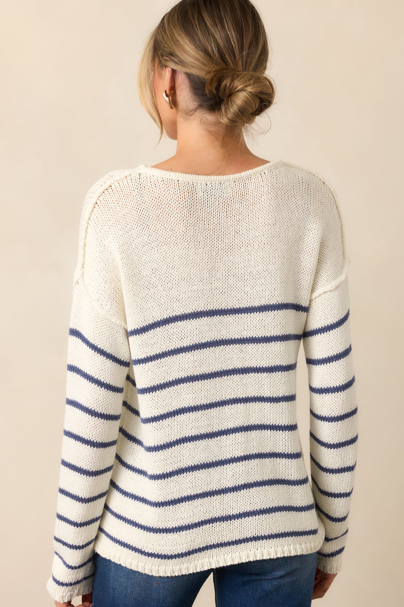 The back of the ivory sweater, showing the smooth fabric and the continuation of the navy stripe pattern across the design.