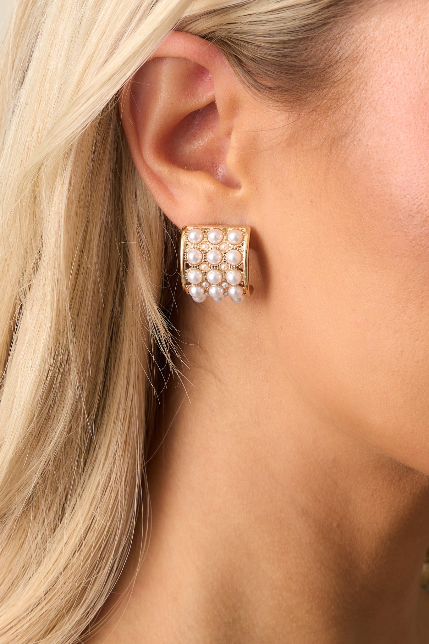 A zoomed-in look at the intricate design of the earrings, focusing on the rows of pearls and the detailed gold border around each faux ivory pearl.
