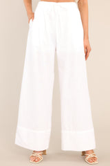 These white pants feature a high waisted design, an elastic waistband with a self-tie feature, functional pockets, and a thick ankle cuff. 