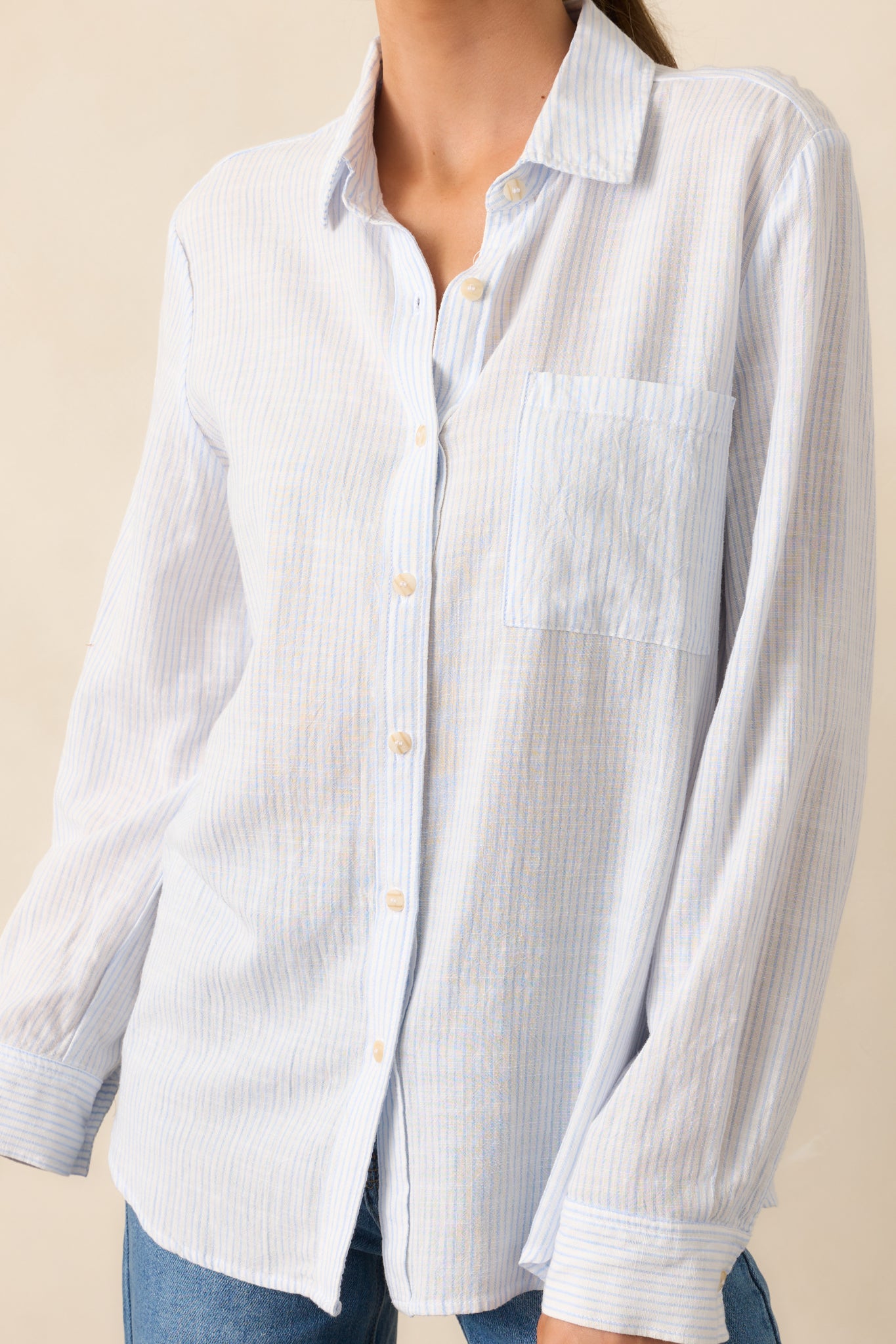 A detailed view of the blue top’s fabric texture, showing the fine stripe pattern and button stitching.