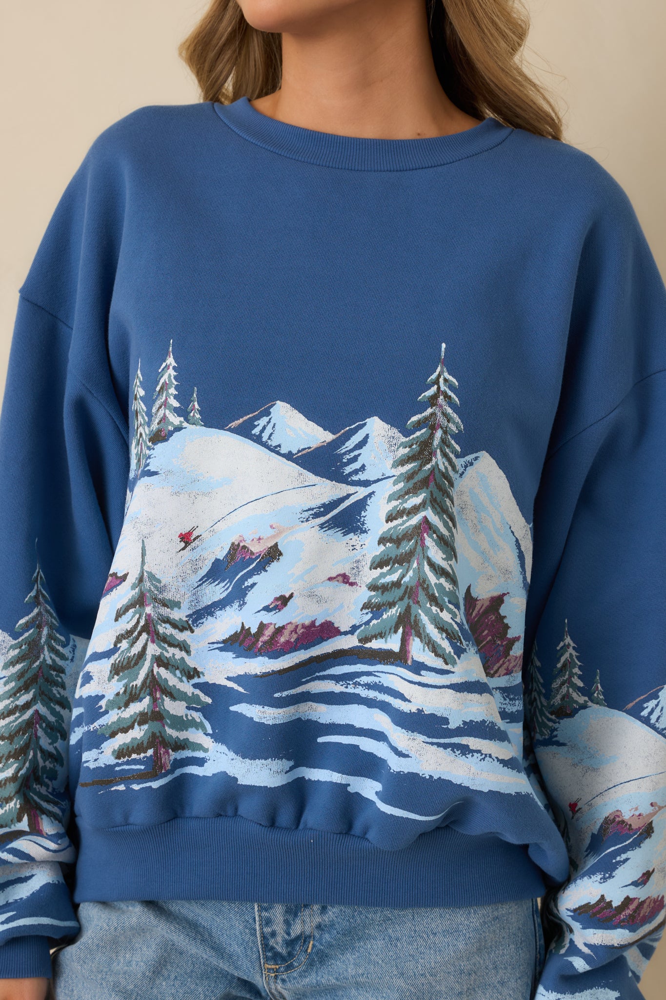 Close view of the dark blue sweatshirt showcasing the ski landscape graphic and ribbed trim texture.